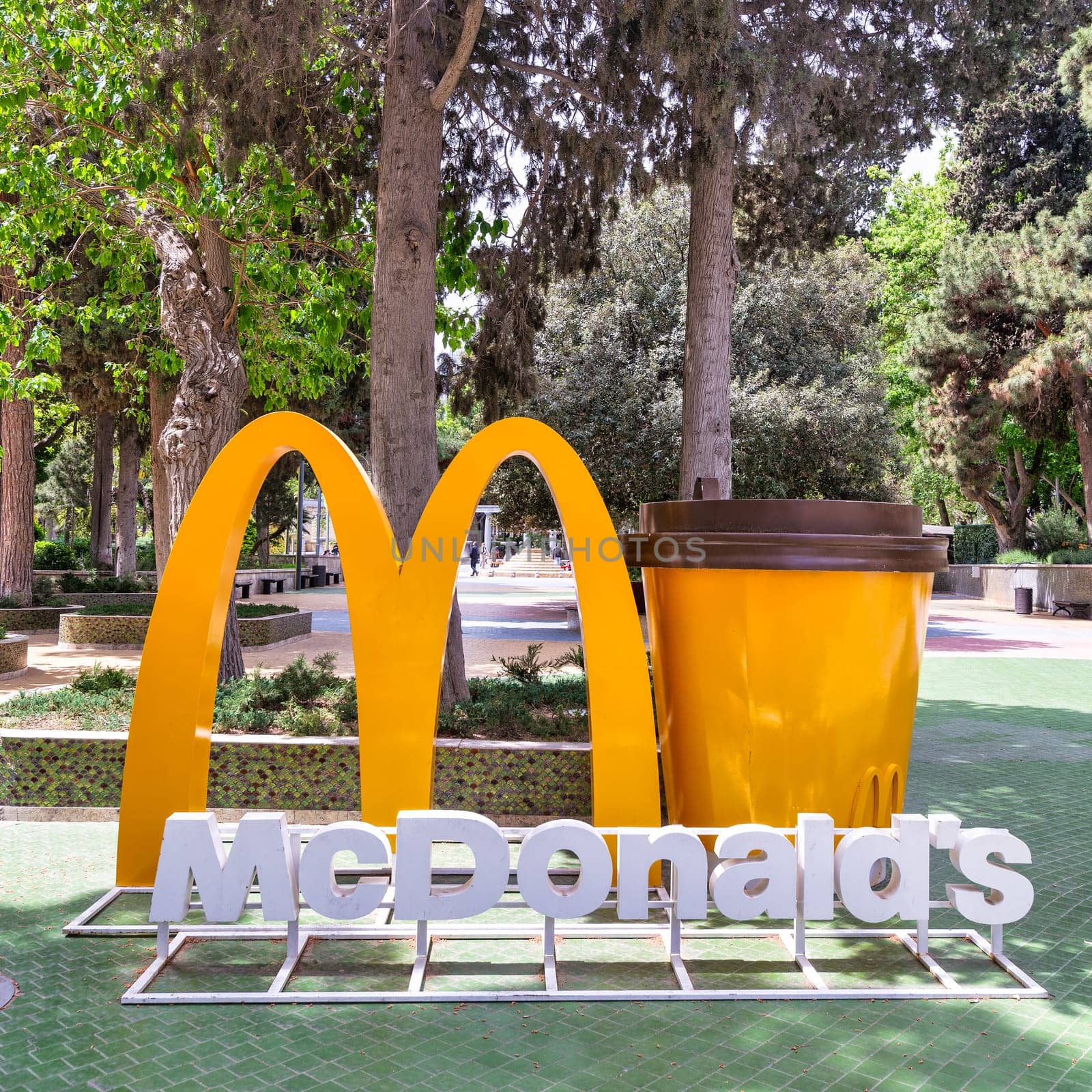 Baku, Azerbaijan - May 5, 2024: A large golden McDonalds archway and cup stand in a park in Nizami Street