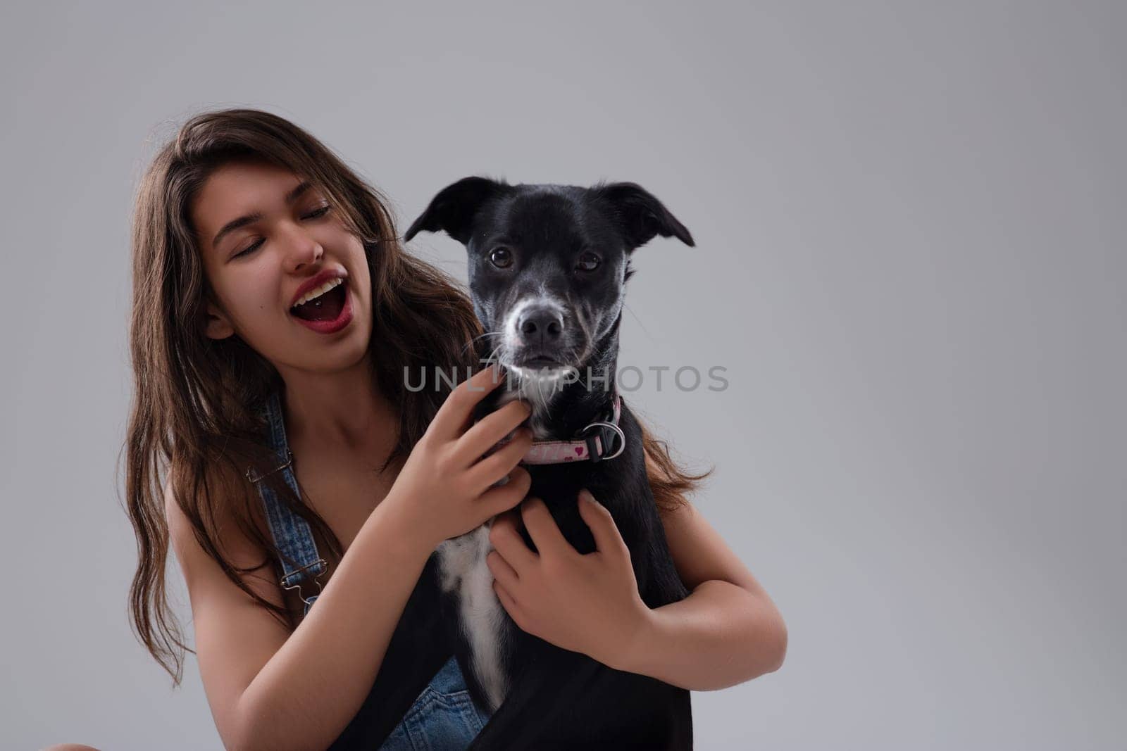 Joyful woman hugs a black and white dog, radiating love and happiness. Their bond is playful and affectionate, showcasing pure joy and companionship