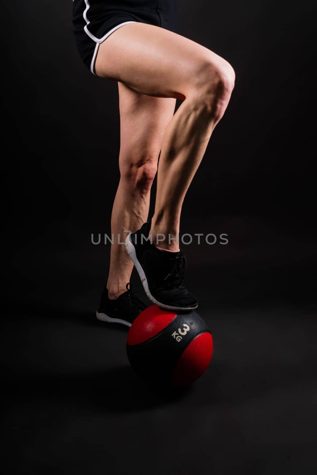 Portrait of a fitness happy fit woman standing holding a medicine ball. Copy Free space for text. Slim caucasian cross fit woman with fitness ball stand in gym, look. Plain light wall background