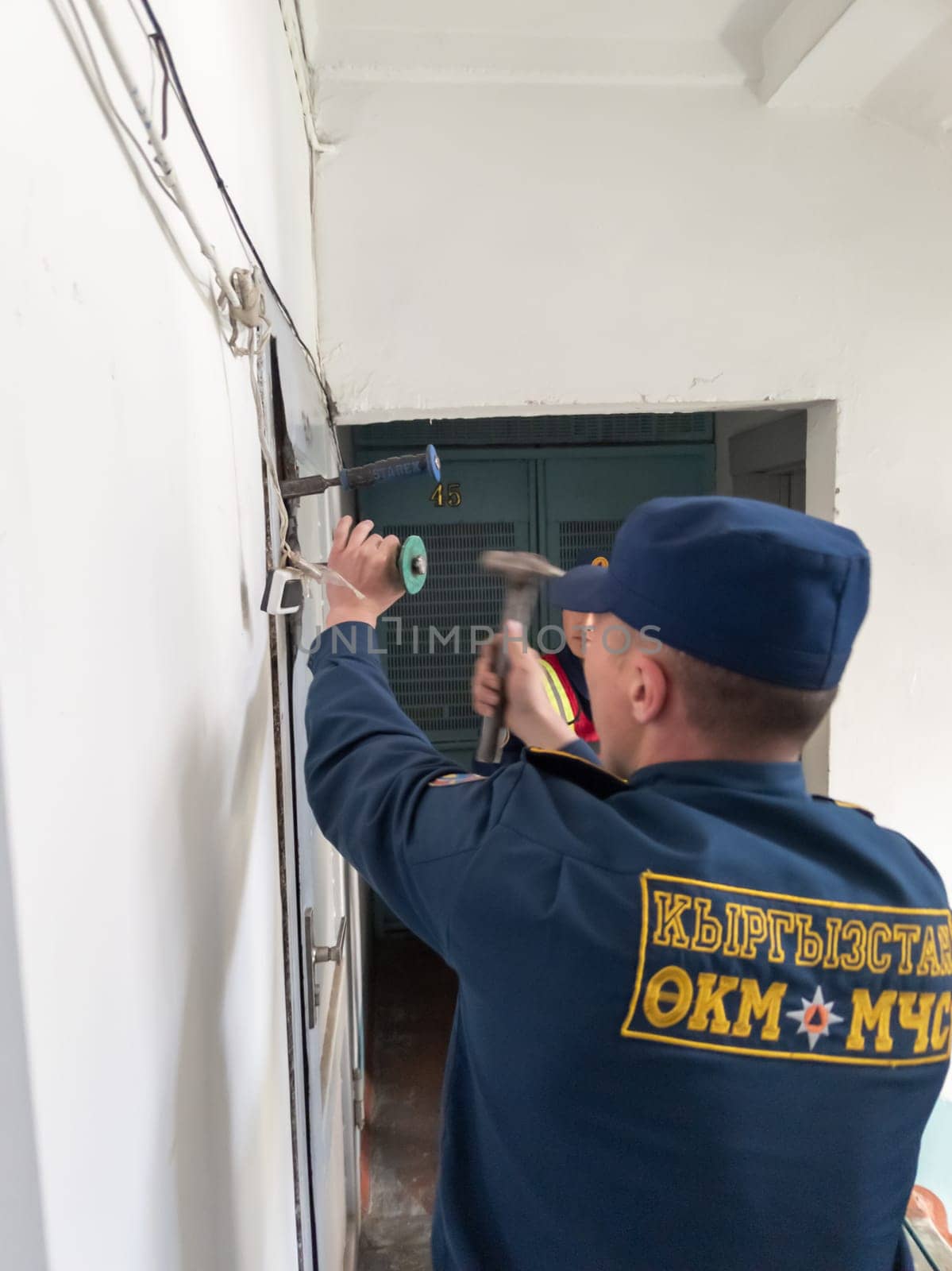 Rescuers from the Ministry of Emergency Situations of Kyrgyzstan break open a metal door to an apartment in an apartment building in Bishkek, Kyrgyzstan April 22, 2023