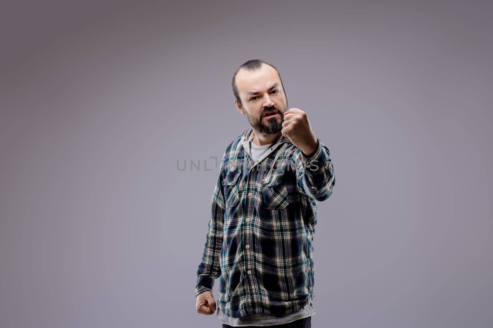 Adult man with a beard is clenching his fists and showing aggression, expressing negative emotions such as anger and rage