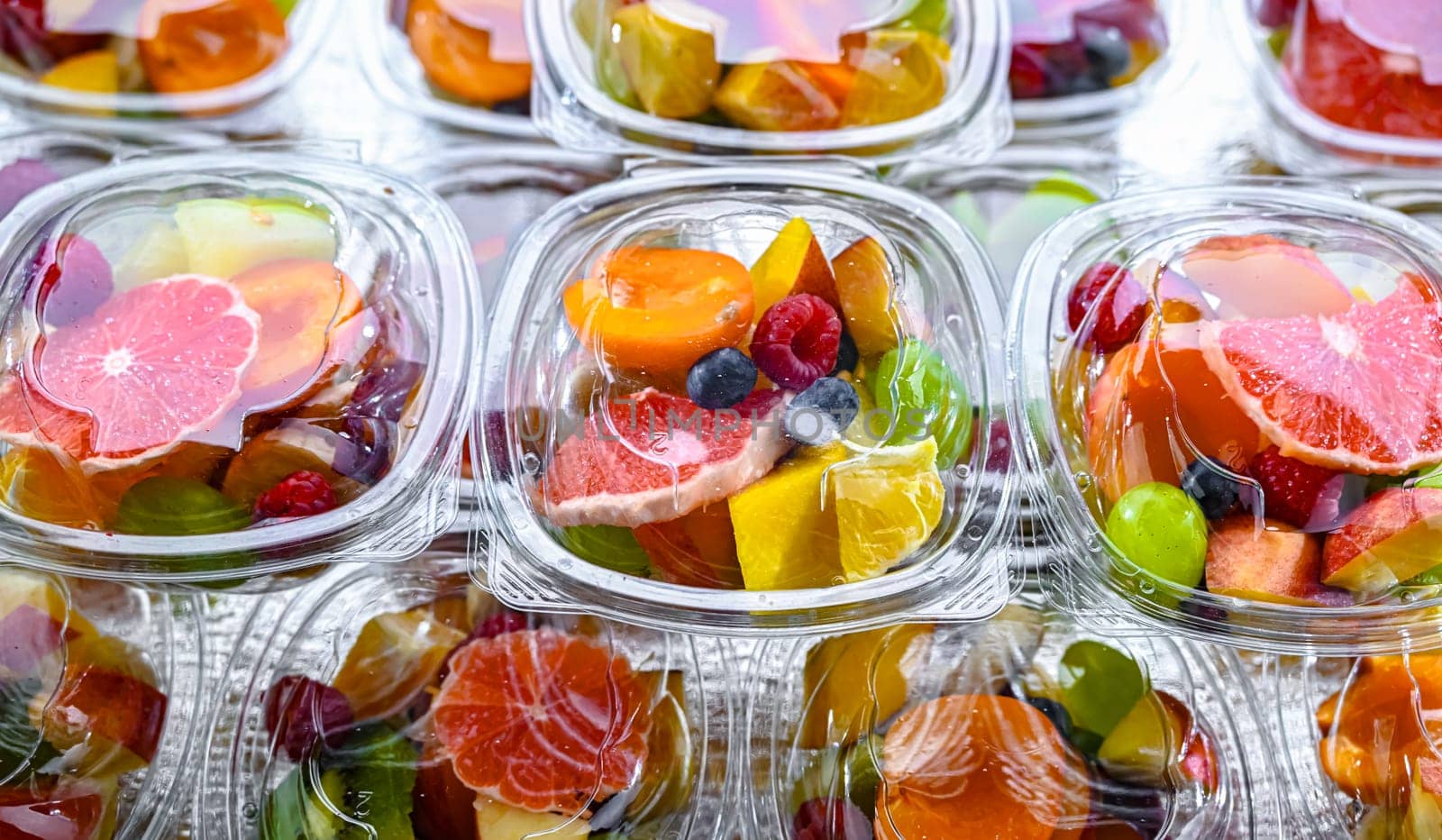 Plastic boxes with pre-packaged fruit salads, put up for sale in a commercial refrigerator