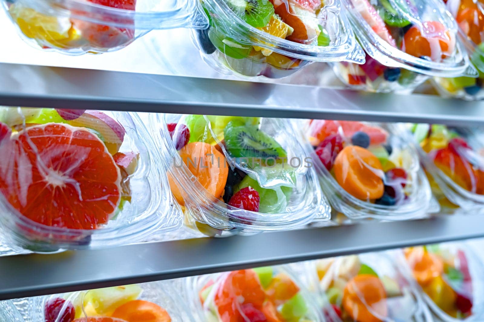 Plastic boxes with pre-packaged fruit salads, put up for sale in a commercial refrigerator