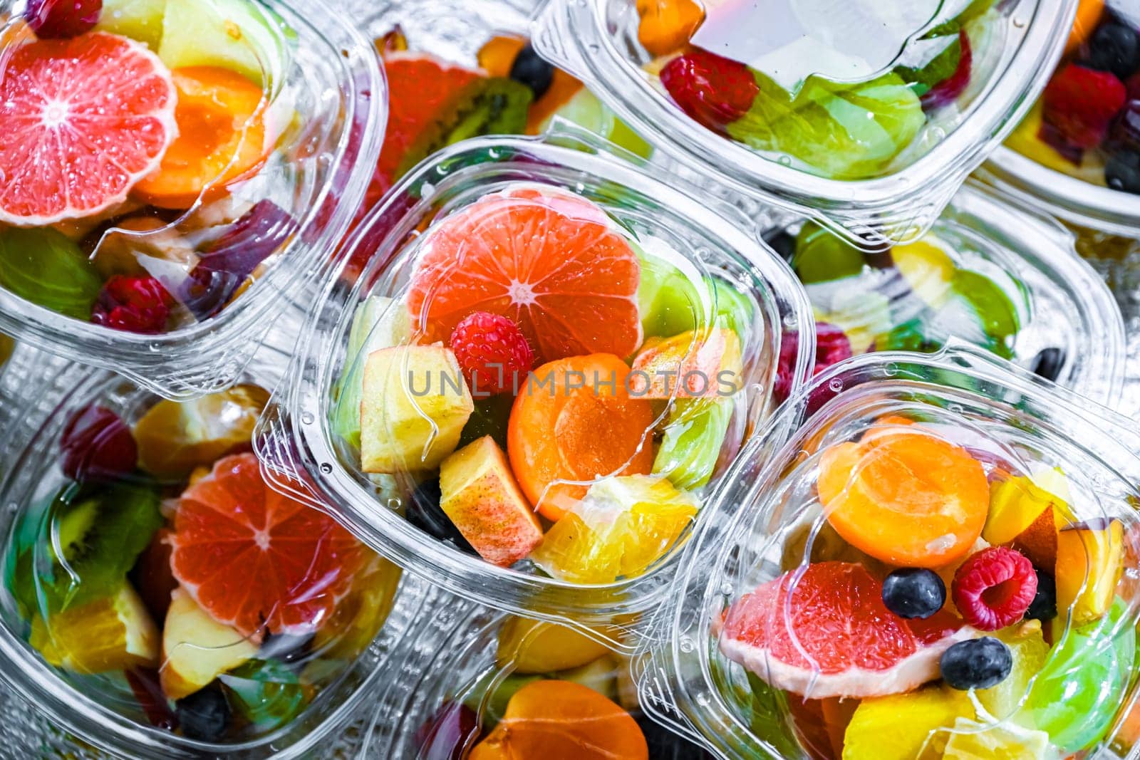 Plastic boxes with pre-packaged fruit salads, put up for sale in a commercial refrigerator