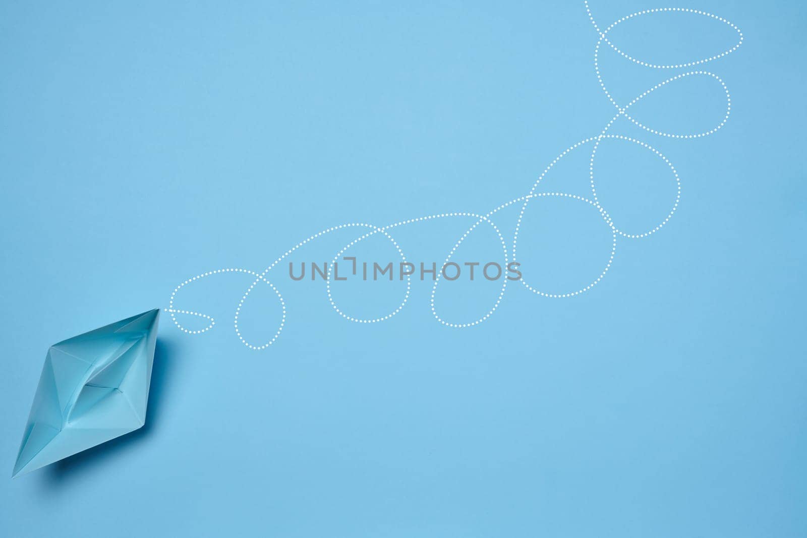 Blue paper boat and a long tangled path, symbolizing the concept of a challenging journey, top view
