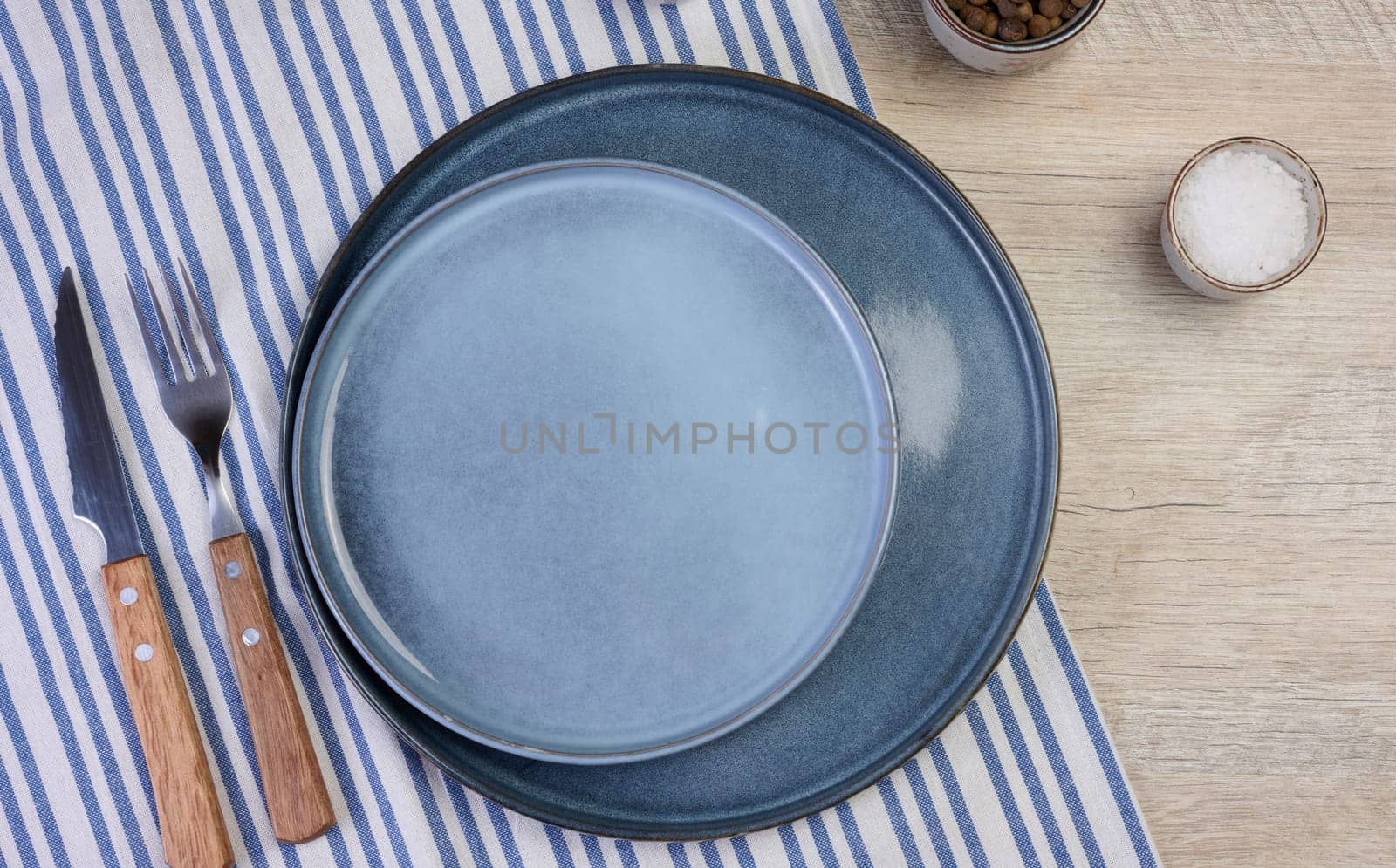 Empty round ceramic plate on the table with spices, top view
