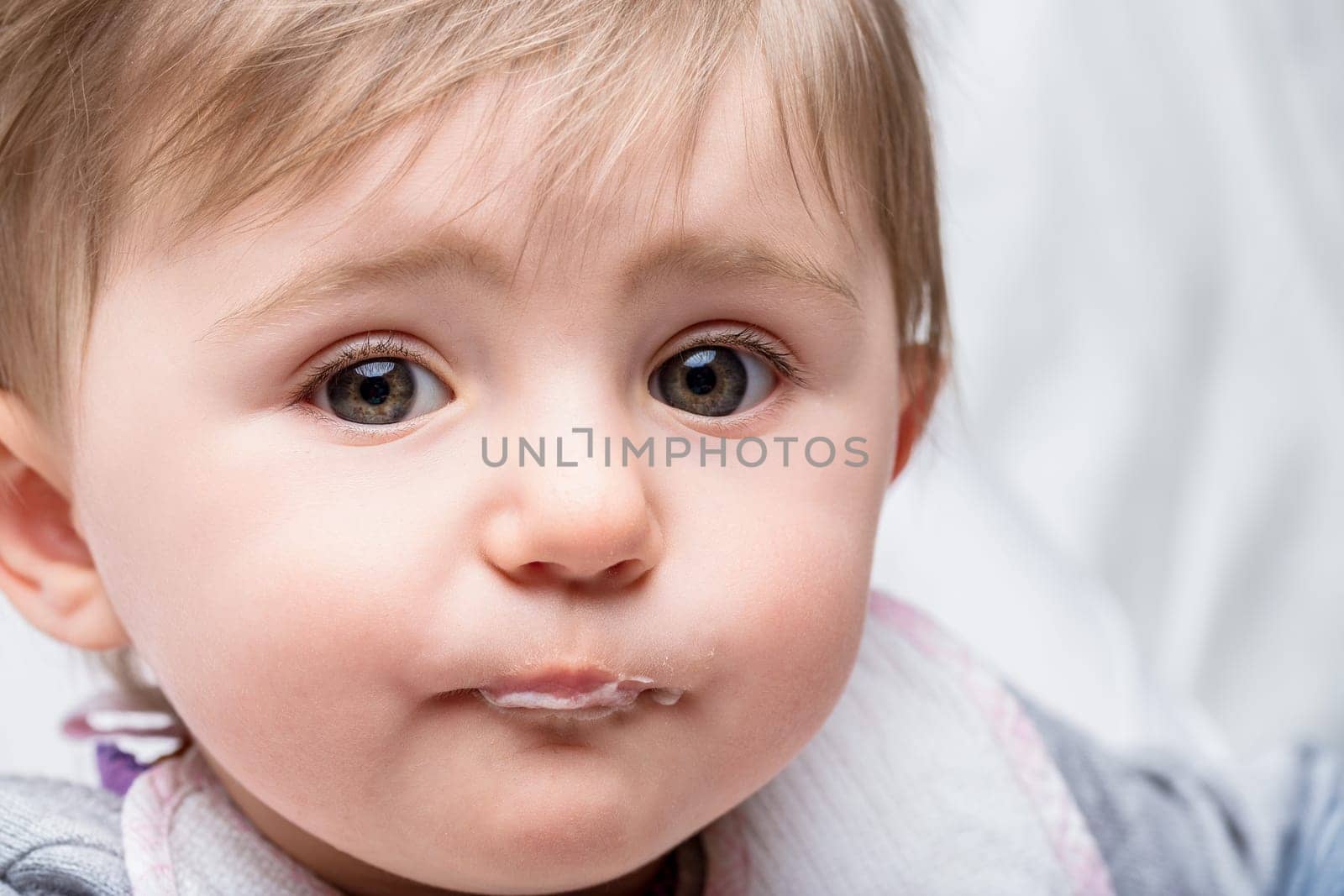Sweet baby girl with drool on her chin makes a funny face, capturing childhood innocence and joy