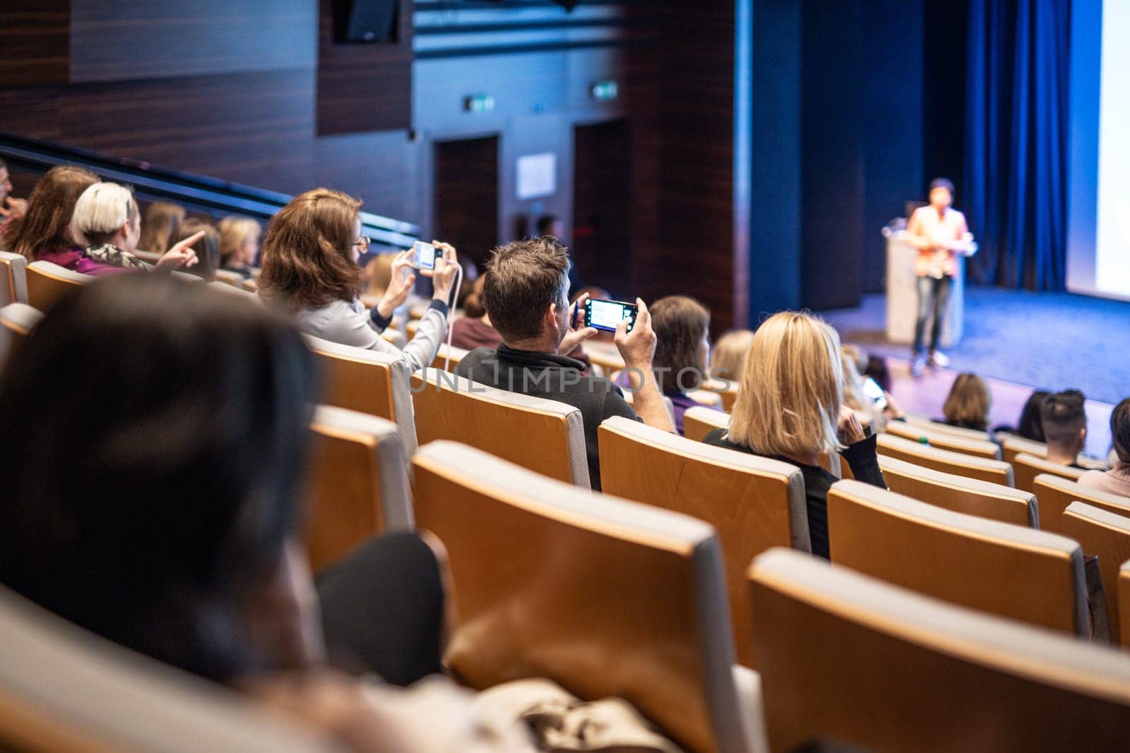 Speaker giving a talk in conference hall at business event. Rear view of unrecognizable people in audience at the conference hall. Business and entrepreneurship concept
