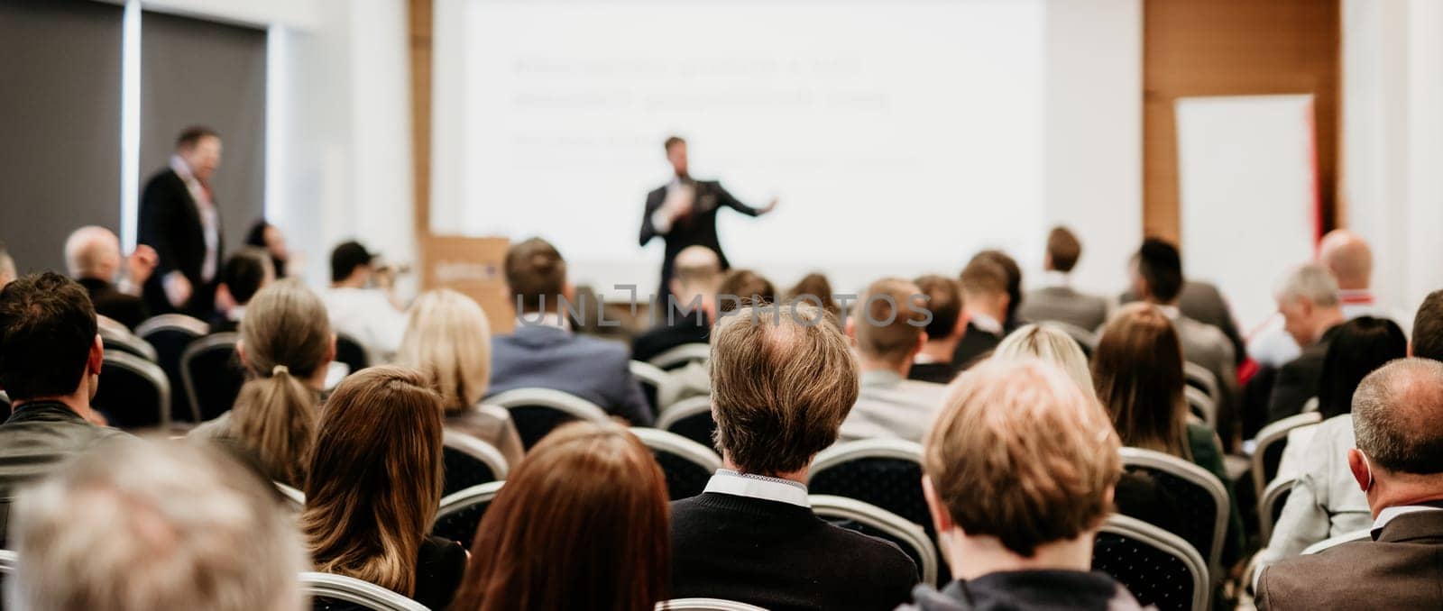 Speaker giving a talk in conference hall at business event. Rear view of unrecognizable people in audience at the conference hall. Business and entrepreneurship concept