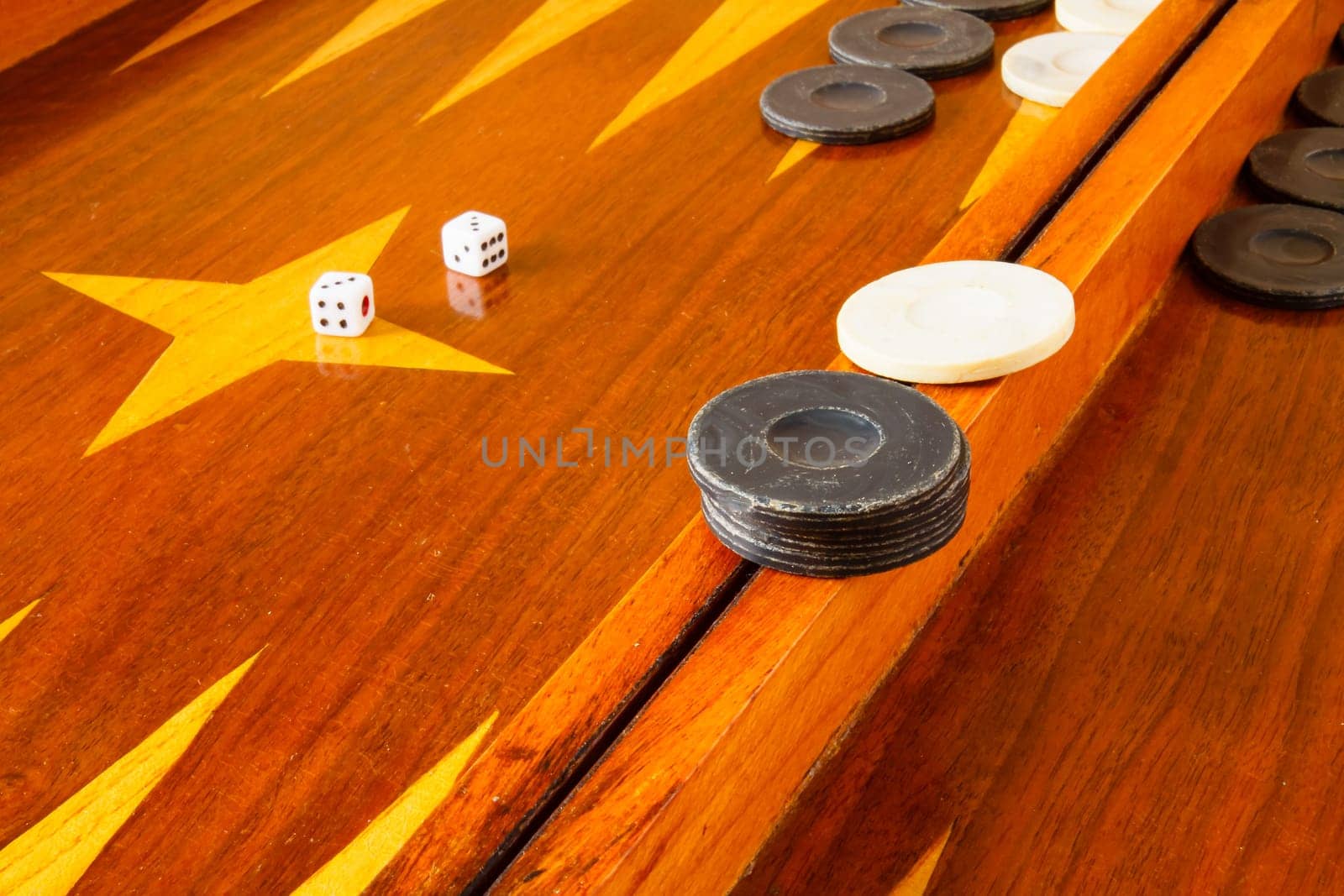 Old varnished wooden board game with plastic checkers and dice. Selective focus with shallow depth of field.