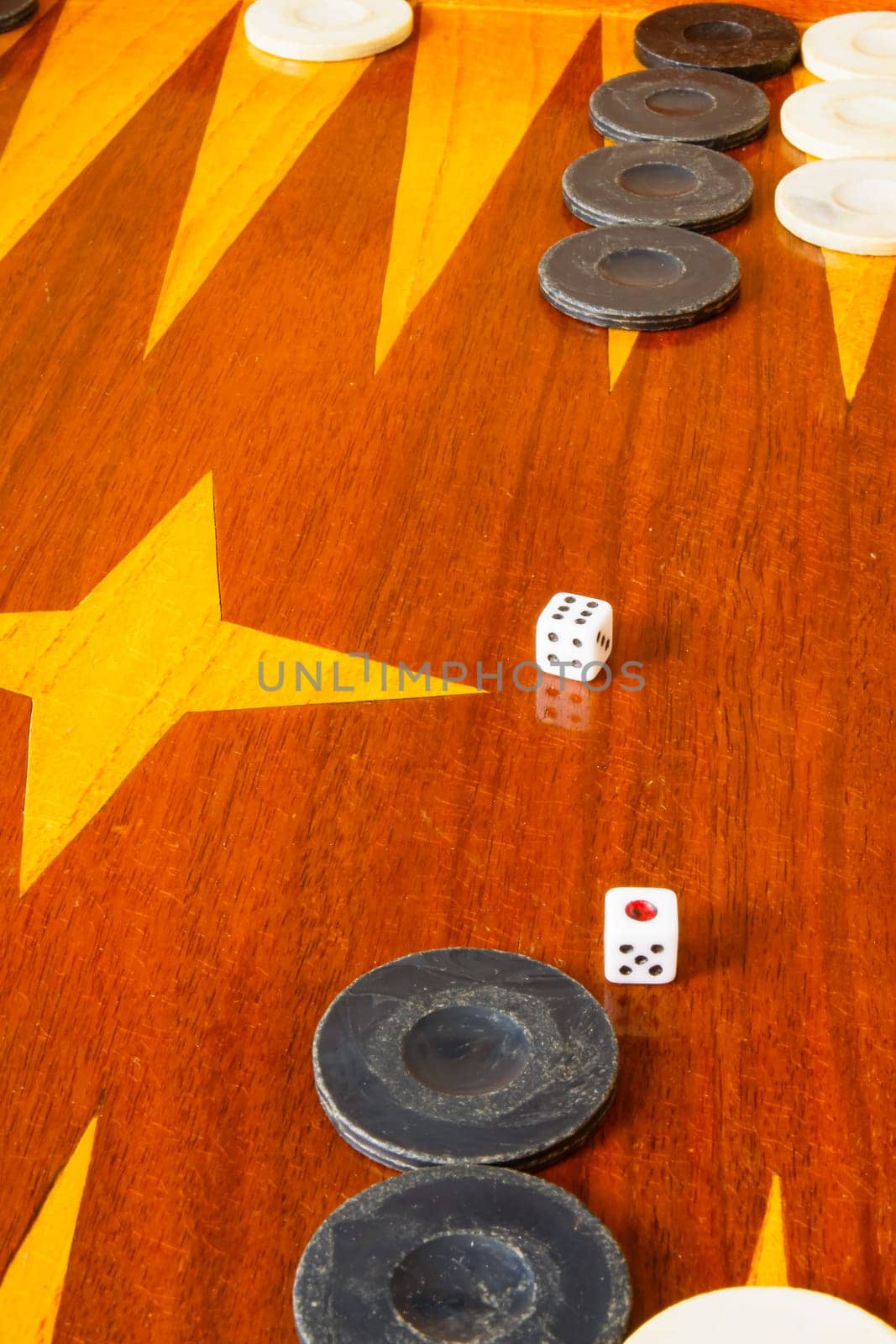 Old varnished wooden board game with plastic checkers and dice. Selective focus with shallow depth of field.