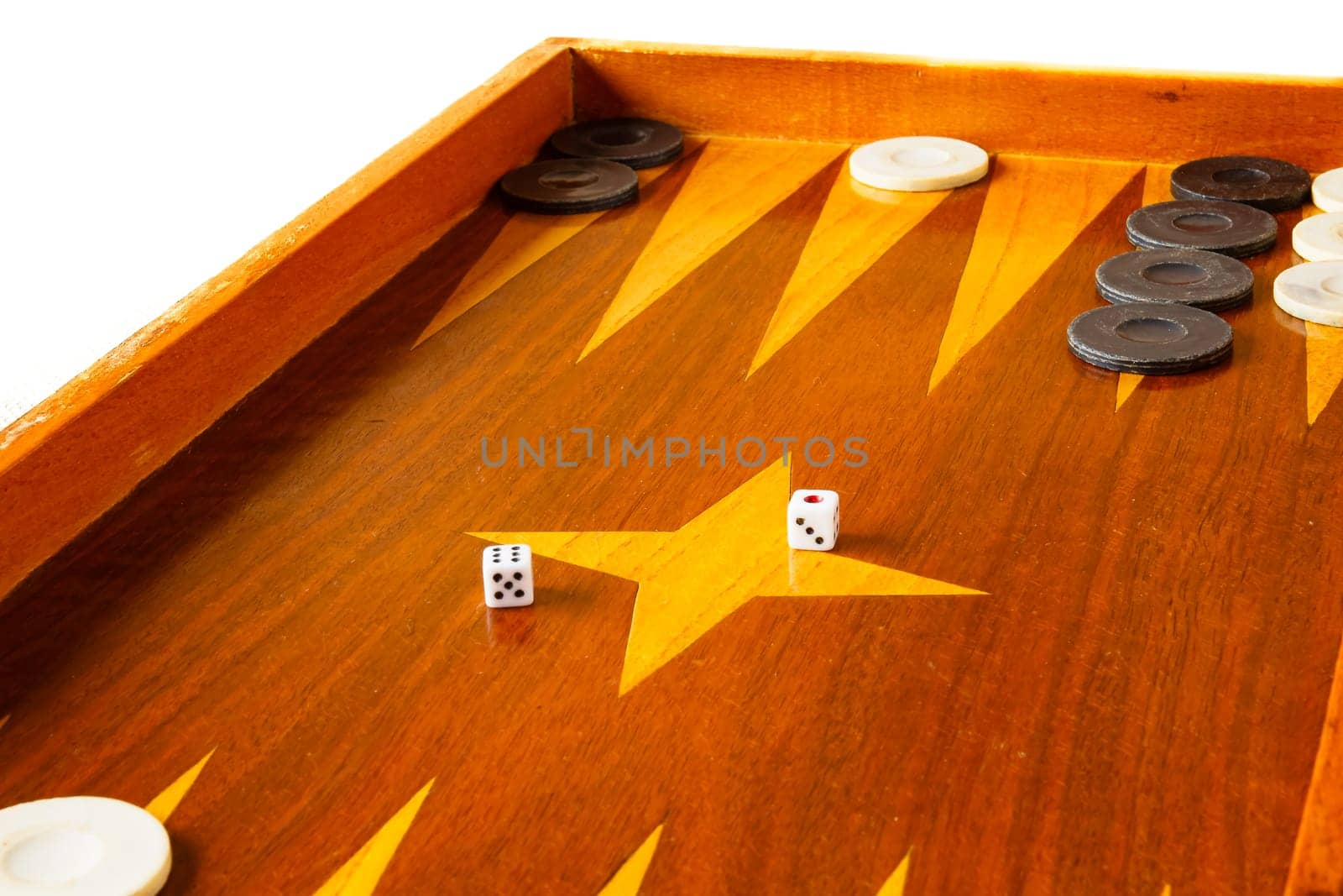 Old varnished wooden board game with plastic checkers and dice. Selective focus with shallow depth of field.