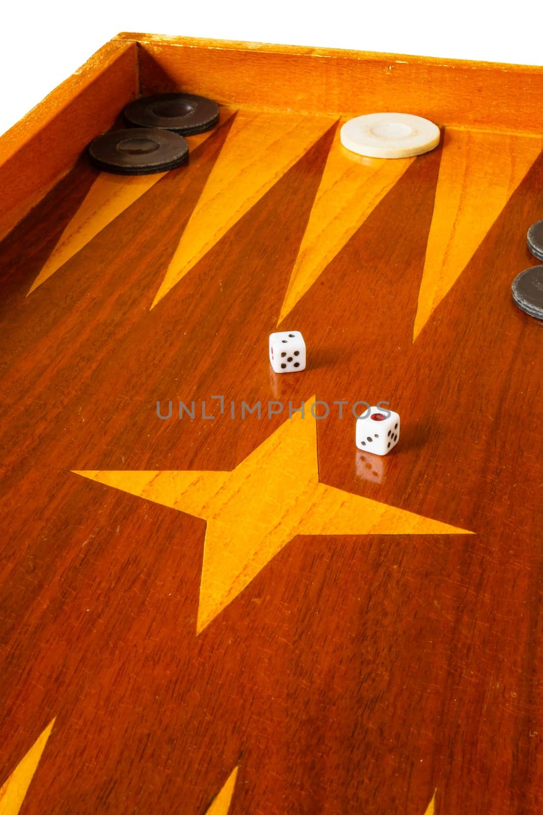 Old varnished wooden board game with plastic checkers and dice. Selective focus with shallow depth of field.