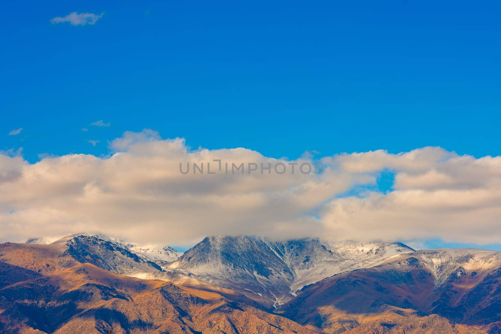 white clouds above snowcapped mountains at autumn afternoon