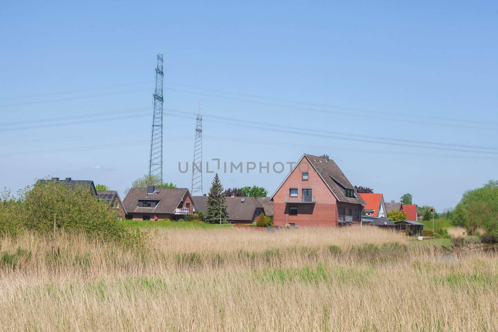 Brick residential building with electricity pylons on the River Este, Buxtehude, Lower Saxony, Germany