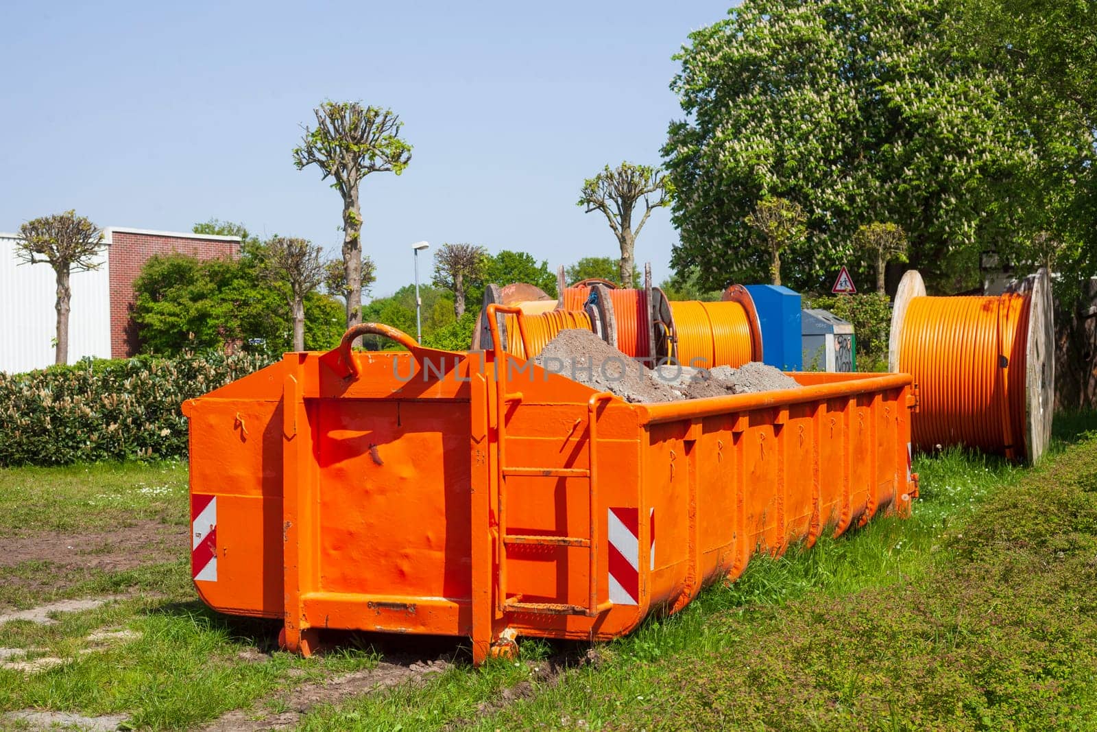 Container, orange skip for building rubble standing on a meadow, Germany