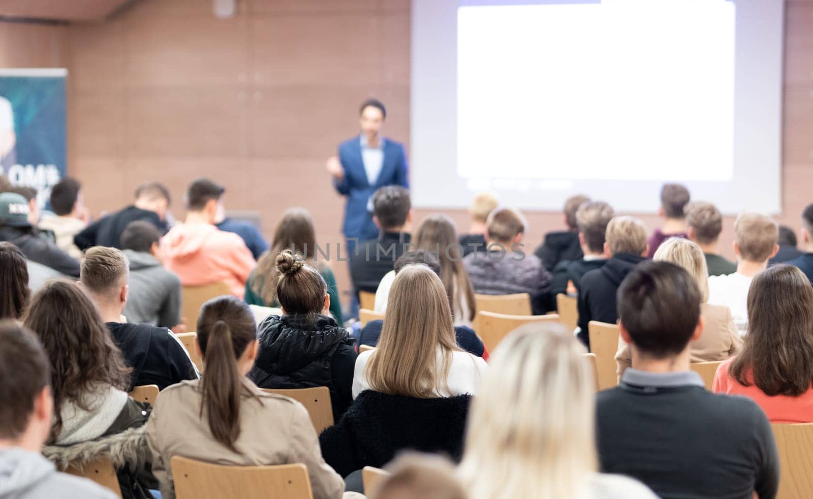 Speaker giving a talk in conference hall at business event. Audience at the conference hall. Business and Entrepreneurship concept. Focus on unrecognizable people in audience.