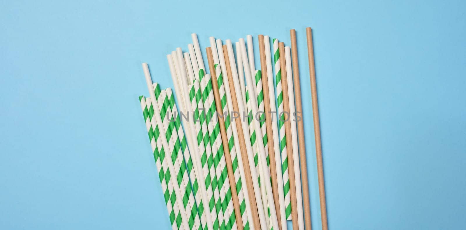 Disposable paper straws on a blue background, top view
