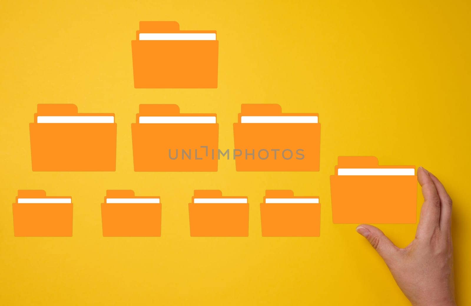 Hand holds a yellow folder over a yellow background with several folders. Concept of control and systematization of documents
