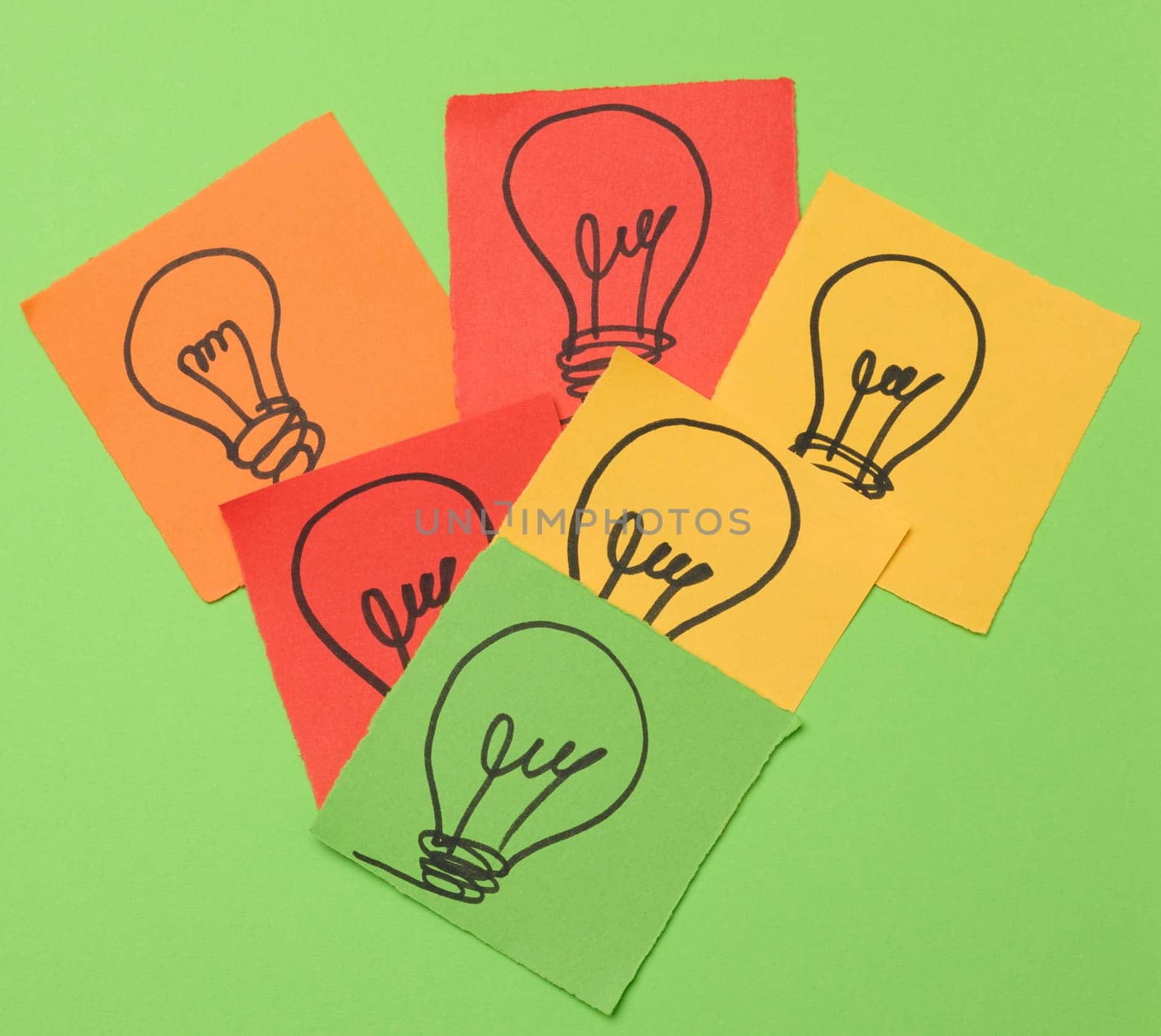 Drawn electric lamps on pieces of paper, the concept of searching for new solutions and ideas