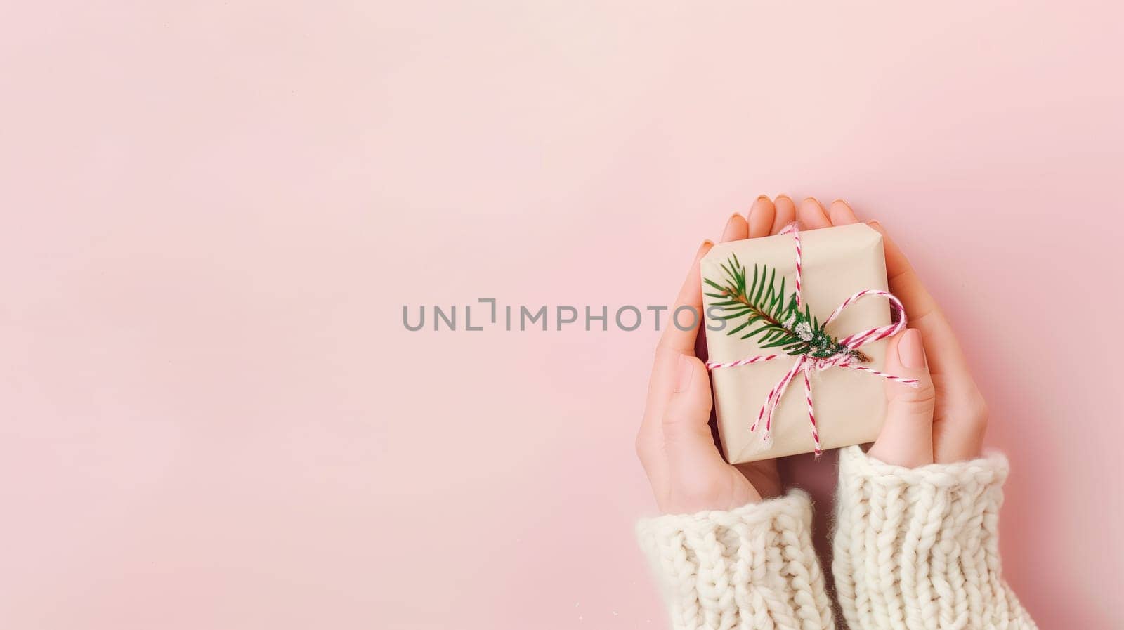 Christmas holiday holding a little gift box with ribbon and fir branch, greeting card, pink pastel background