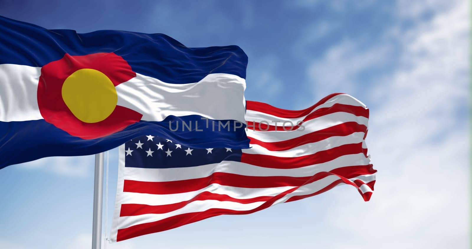 The Colorado state flag waving with the national flag of the United States of America on a clear day. 3D illustration render. Rippled textile