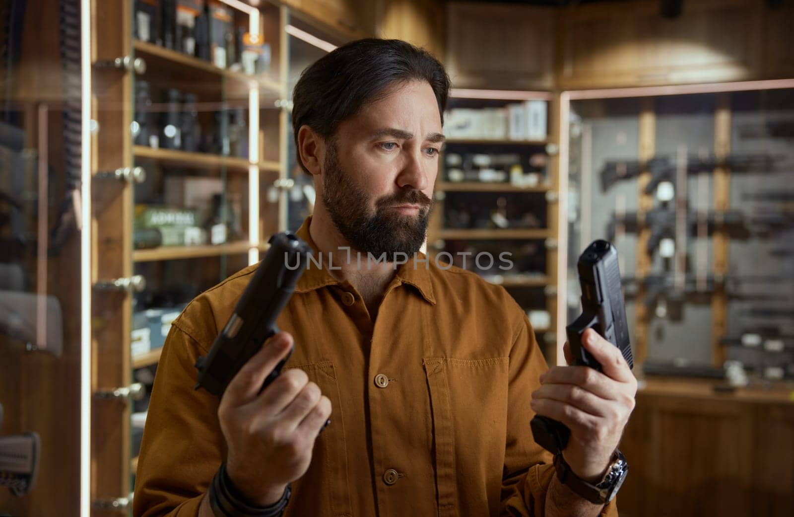 Portrait of mature male in shop merchant with two handguns aiming. Firearms for self-defense, legalization of weapons for civilians people