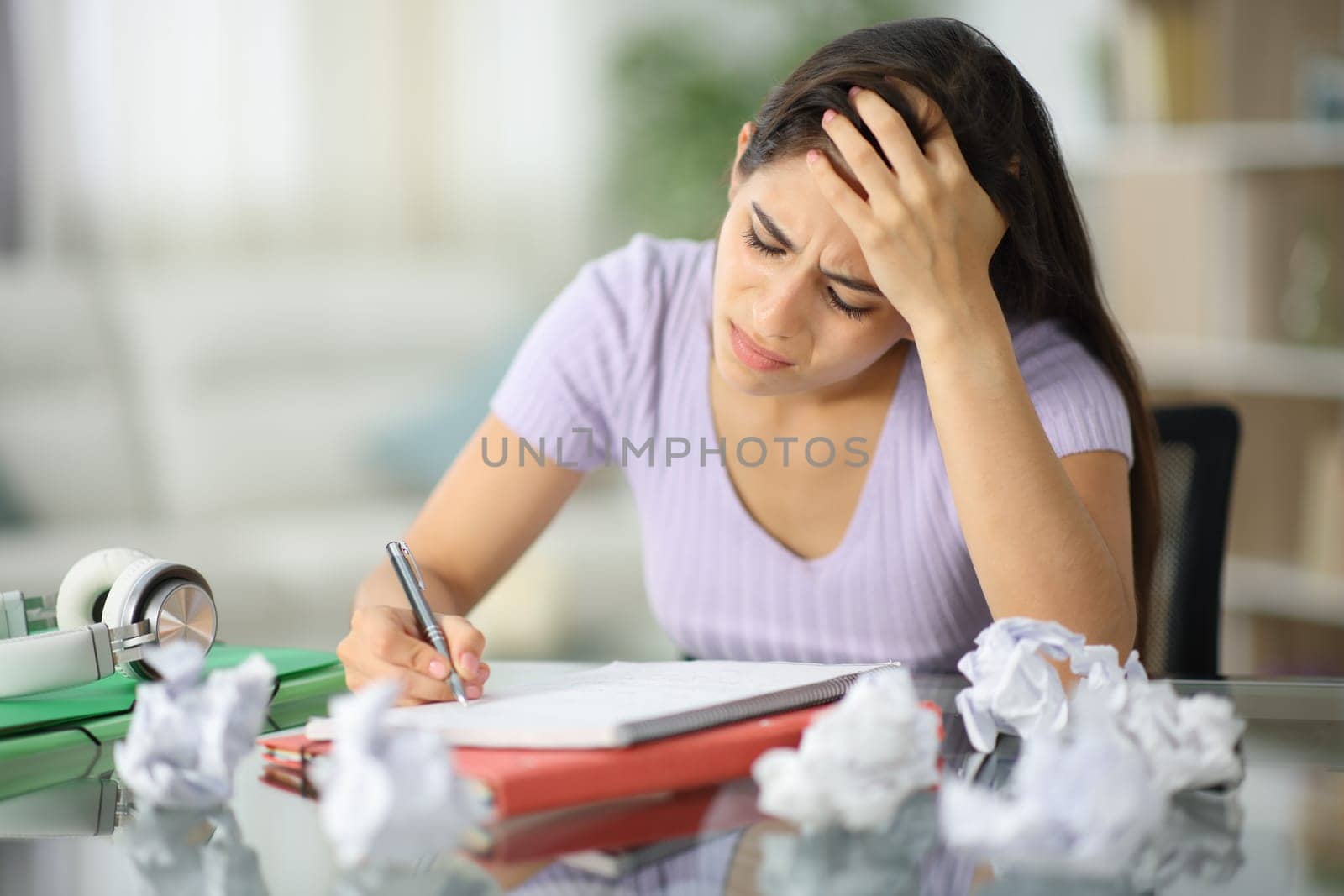 Frustrated student crumpling papers trying to do homework at home