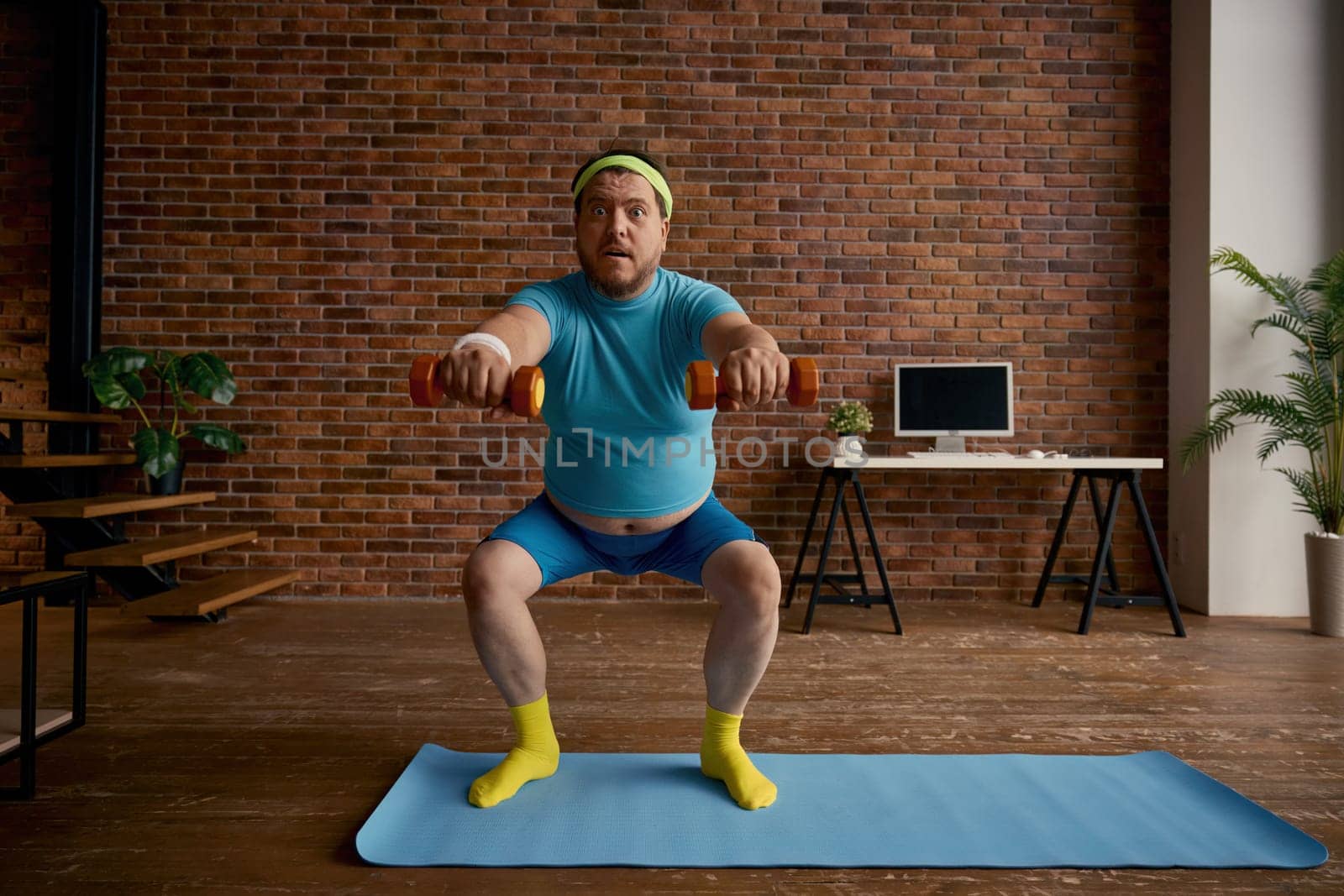 Stubborn fat athlete doing squat with dumbbells enjoying sport for weight loss. Physical exercise at home for healthy lifestyle