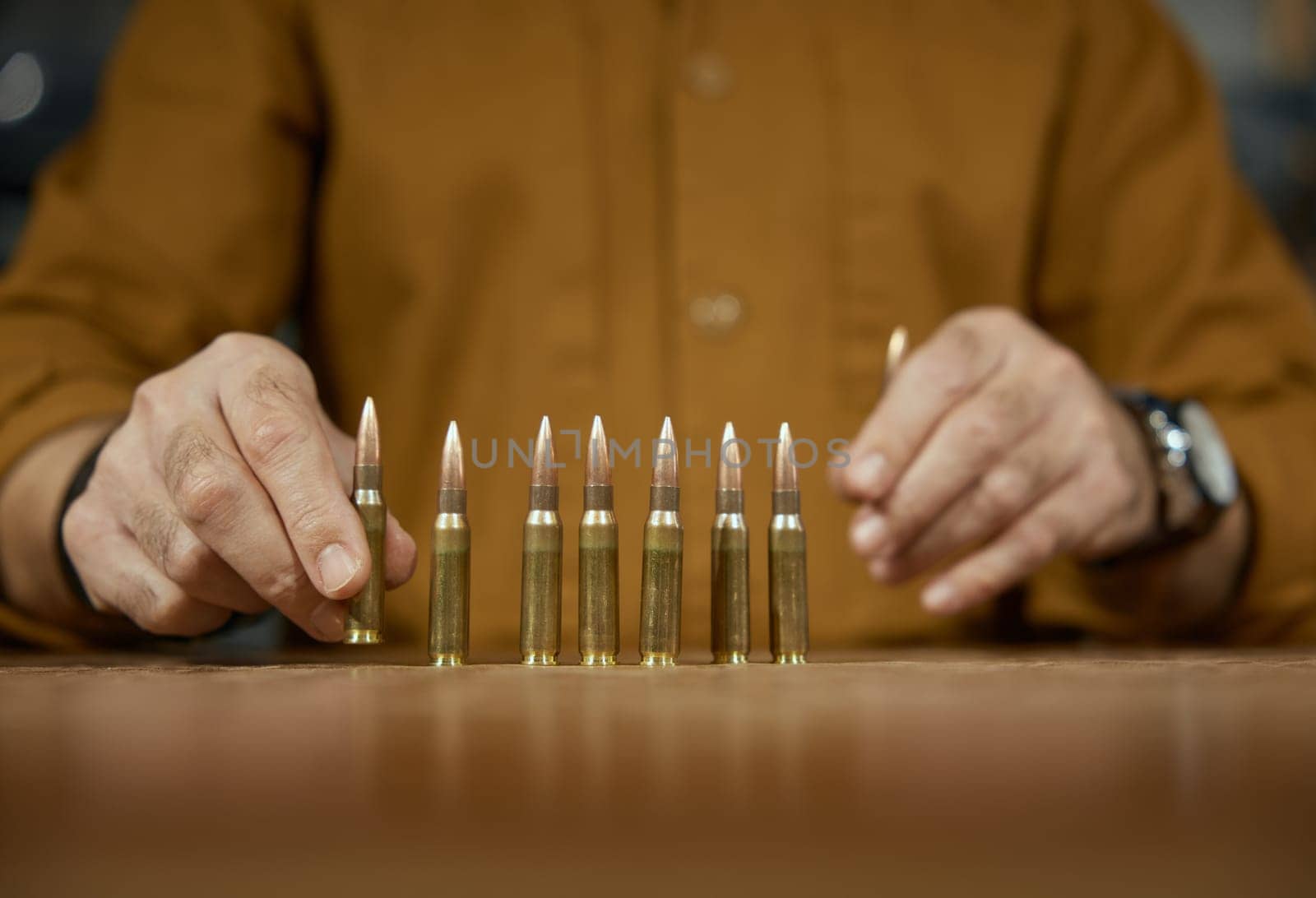 Salesman puts out firearm cartridges for customer on counter desk closeup. Weapon shop with military ammunition for army and special forces