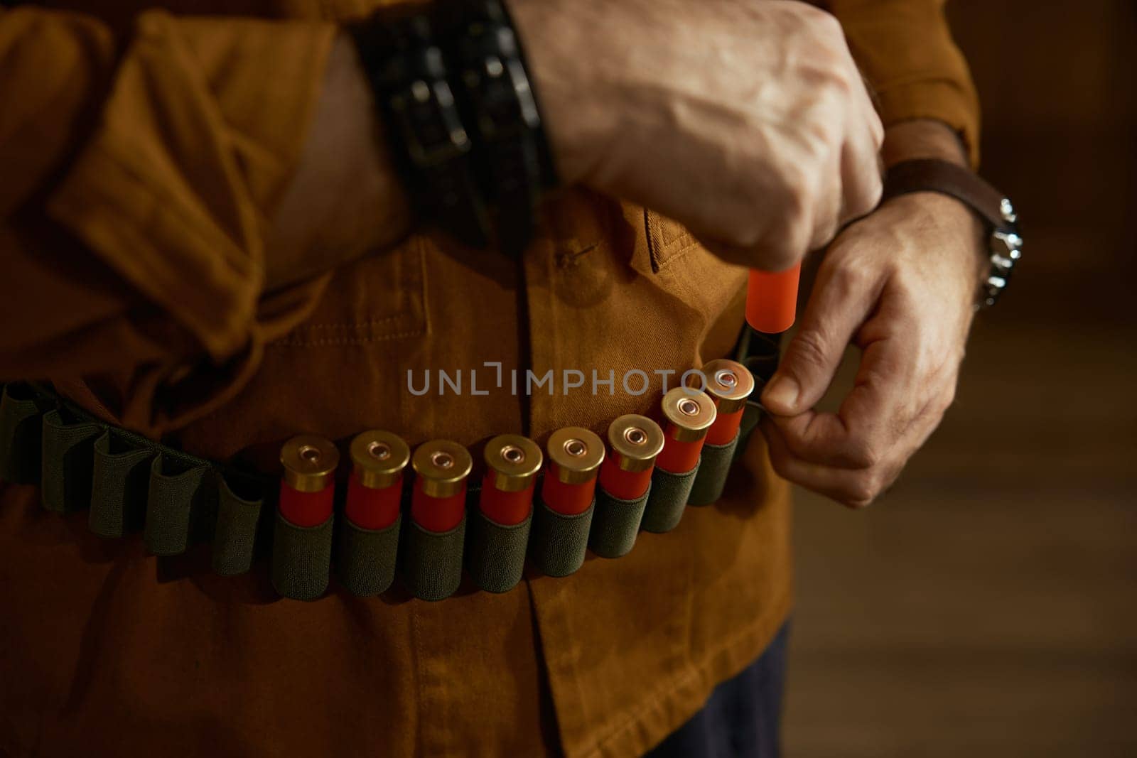 Closeup of hunter hands placing bullets into the ammo belt. Hunter weapon shop with military arsenal assortment concept
