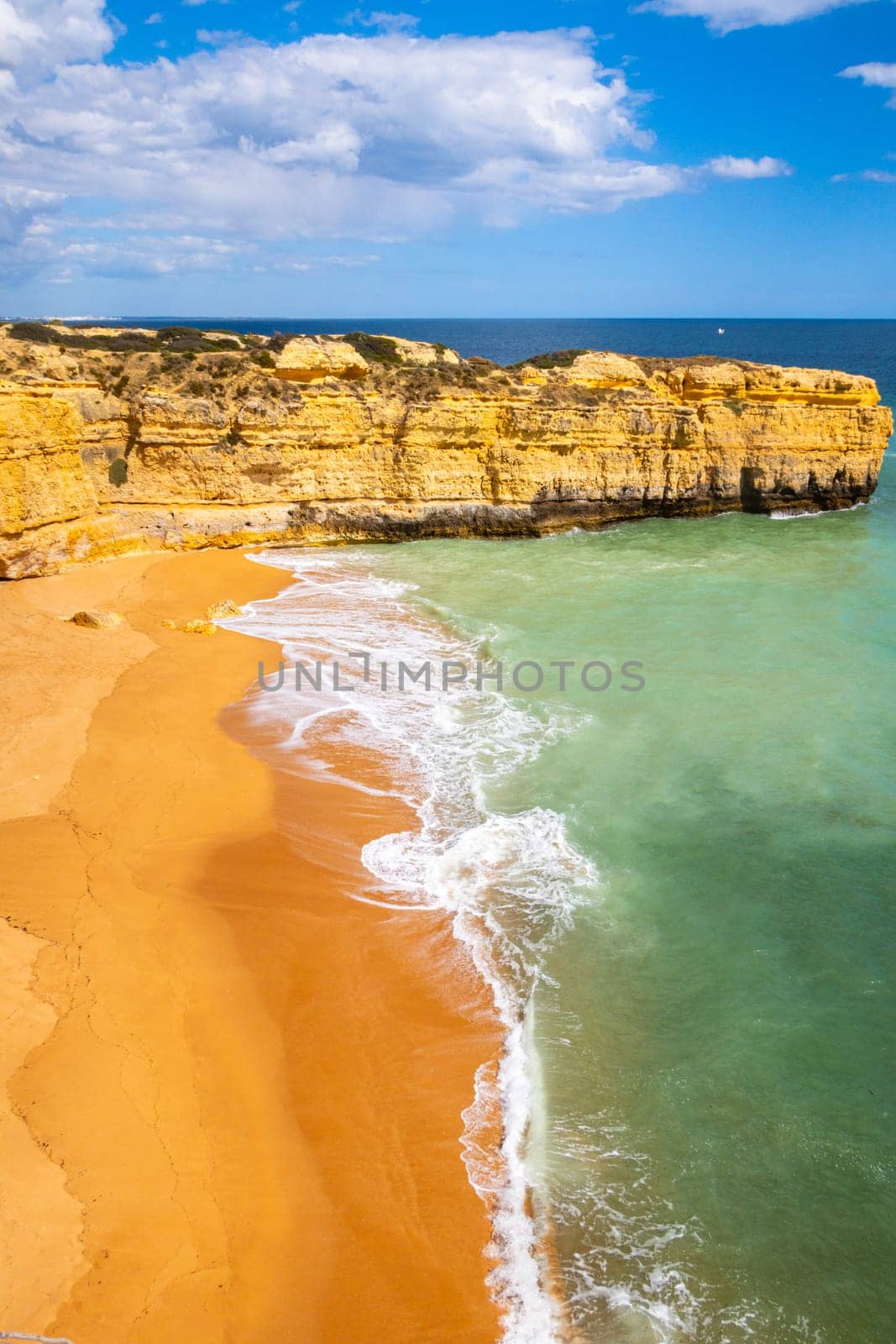 Vertical view over cliffs and ocean waves crashing onto Praia da Ponta Pequena beach near Albufeira, Algarve, Portugal