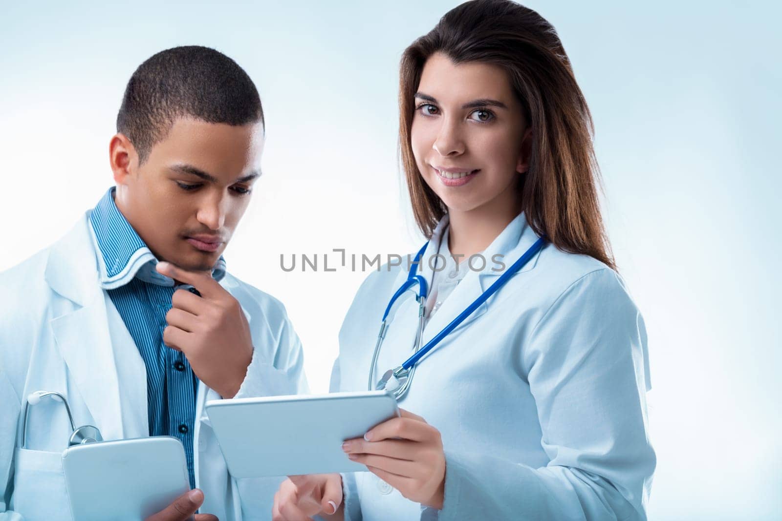 Two healthcare professionals discuss a patient's report on a tablet, showing teamwork and compassion in a hospital