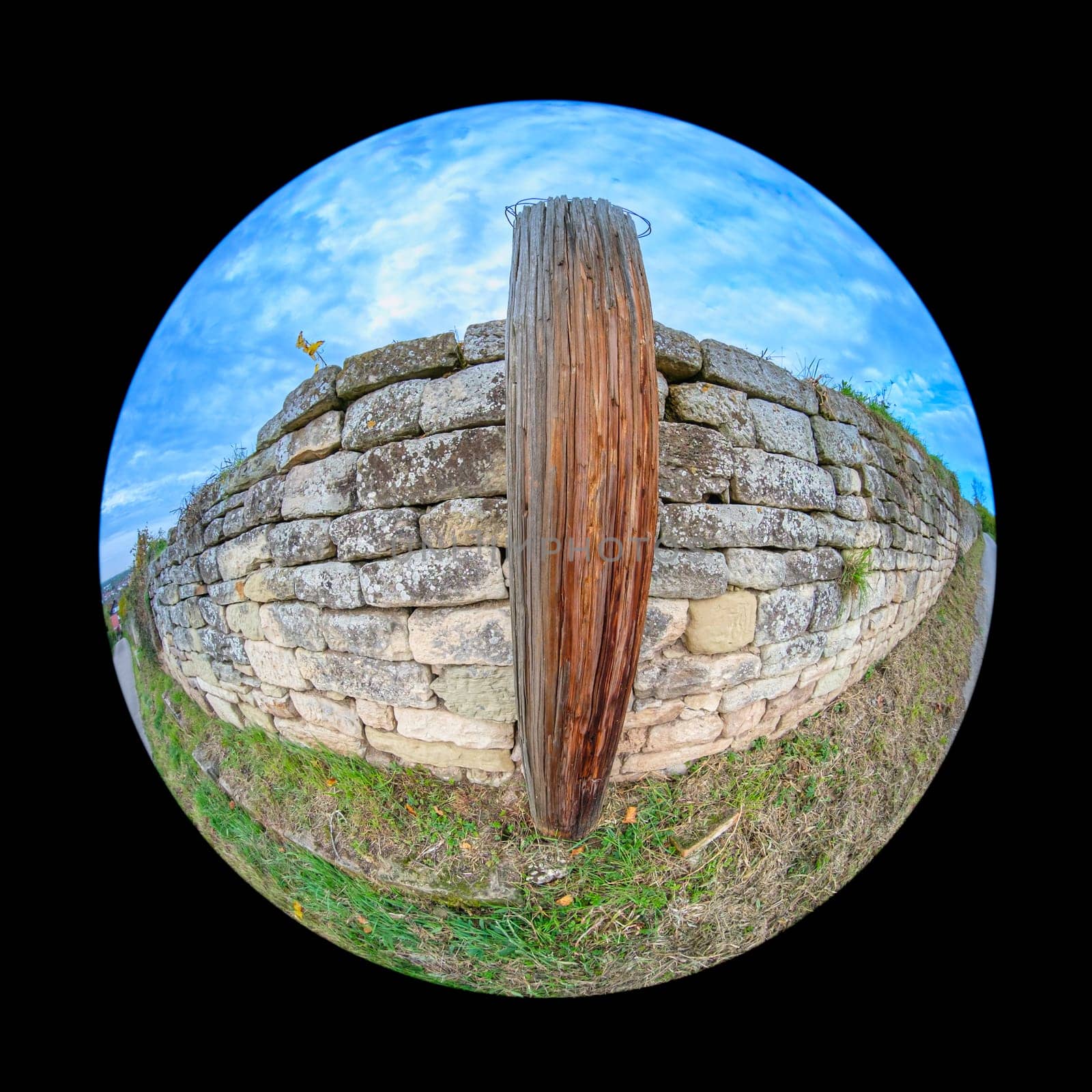 Old wooden post and ancient stone wall exterior with fish-eye distortion