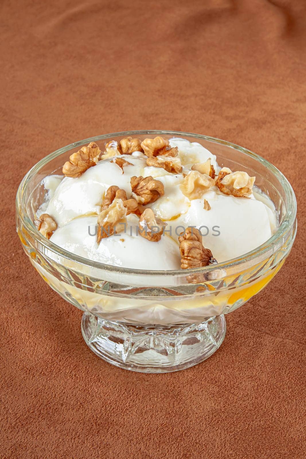 Yogurt dessert with honey and walnuts in a glass bowl. Selective focus with shallow depth of field.