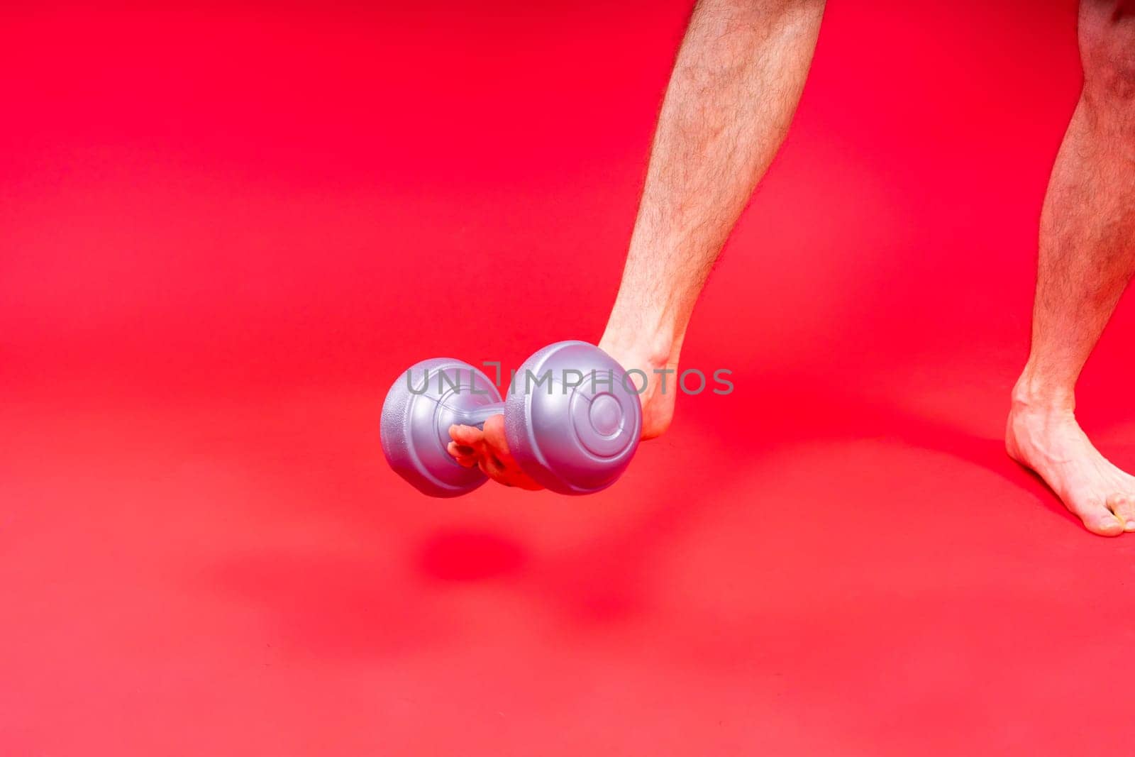 Adult muscular man smiling and screaming while working out hard with a dumbbells.