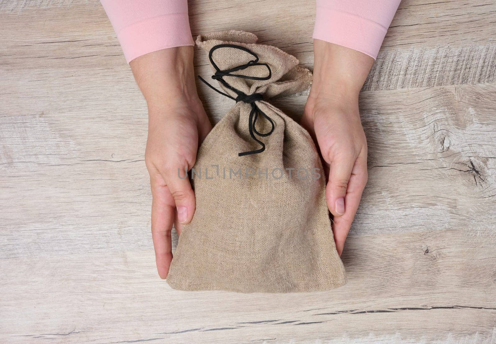 Female hands holding a stuffed canvas bag, concept of wealth and success