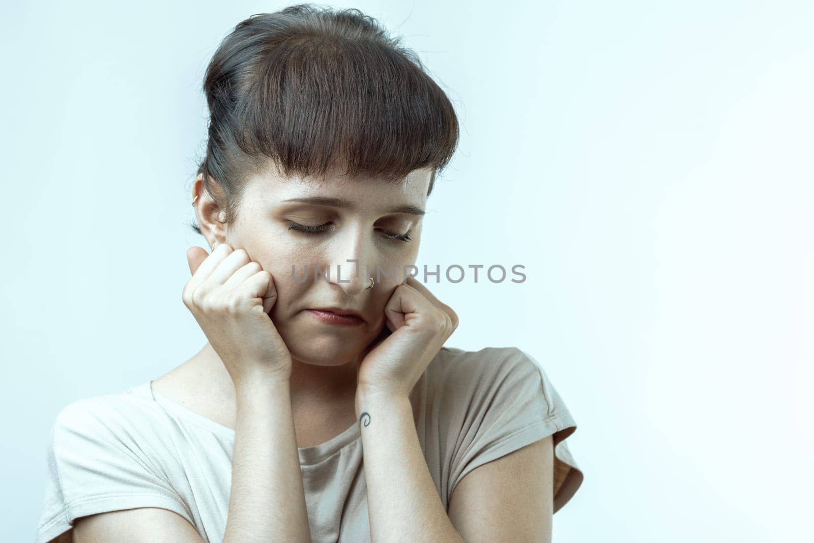 Young woman holds her head in her hands, showing deep sadness and loneliness. She looks overwhelmed by negative emotions like despair and grief, reflecting inner turmoil
