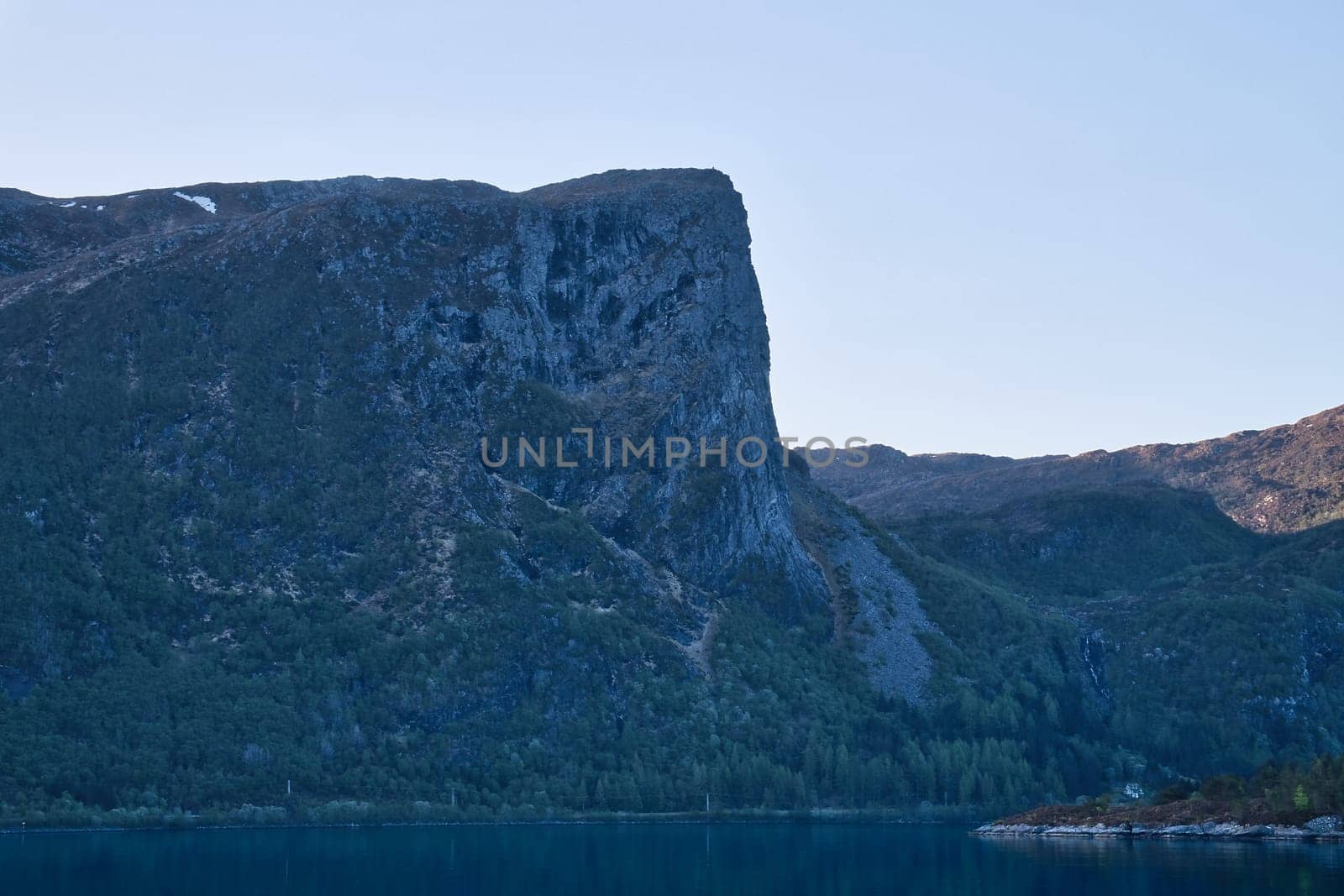 Norwegian fjord landscape. View of mountains with rugged vegetation. Crystal clear water in the foreground. Landscape from Scandinavia