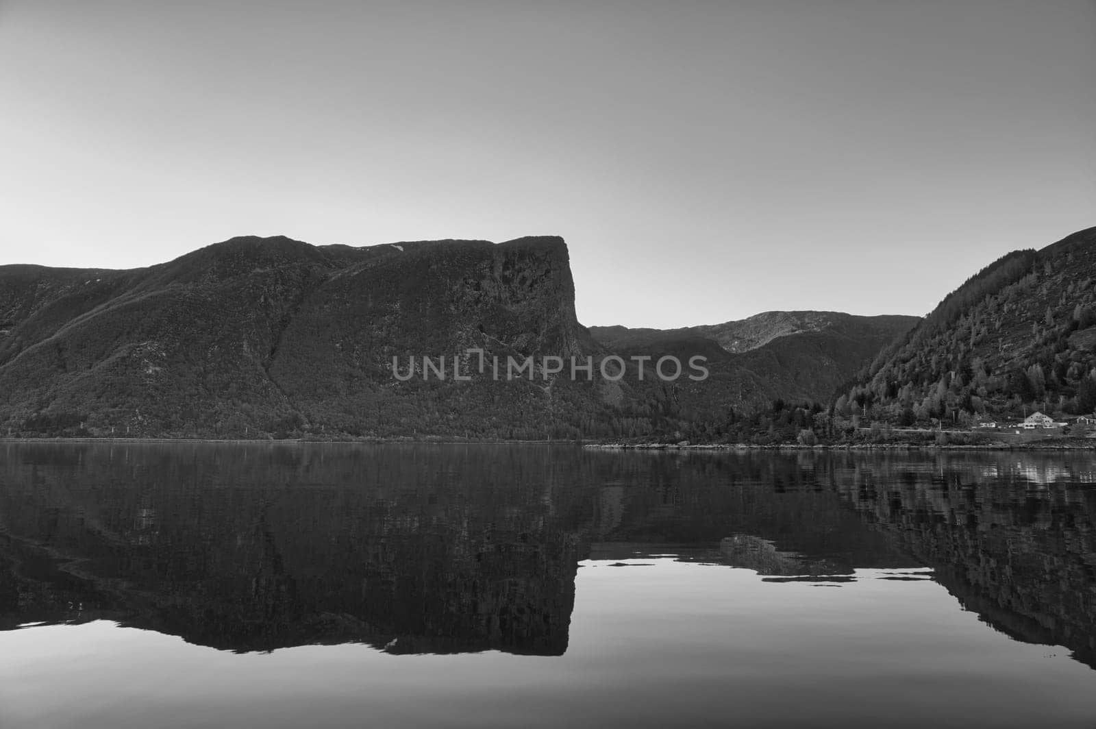Norwegian fjord landscape. Mountains with rugged vegetation in black and white. Crystal clear water