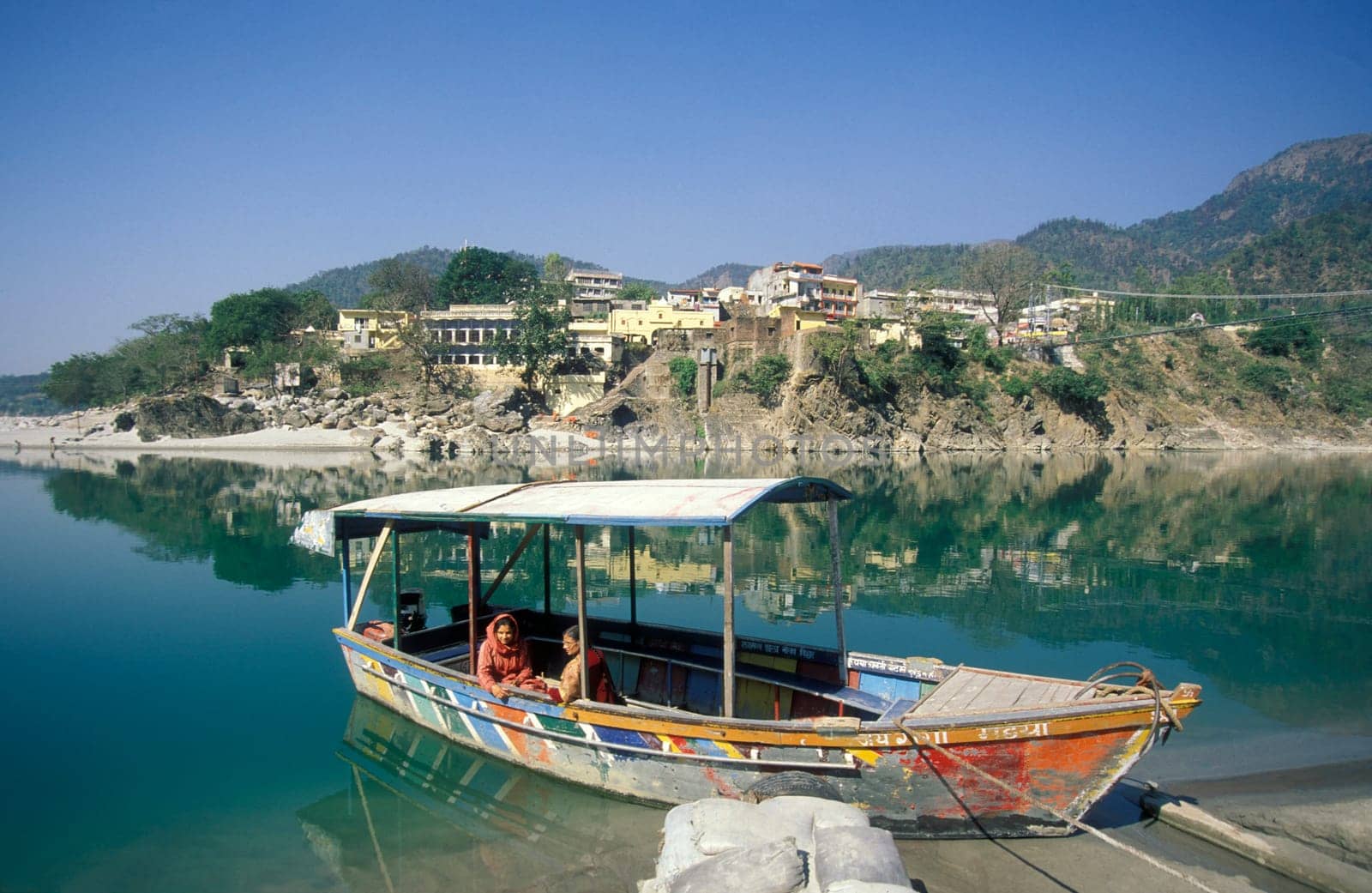 a Boat on the Holy Ganges River with the city of Rishikesh in the Province Uttarakhand in India.  India, Rishikesh, February, 1998