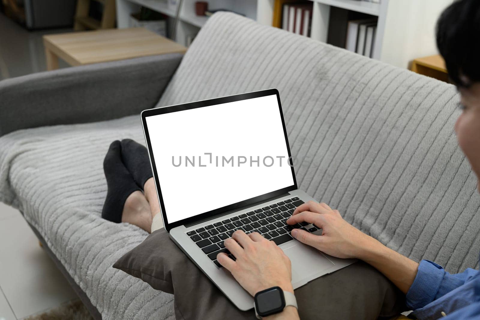 Man hands using laptop with blank screen on sofa at his living room.