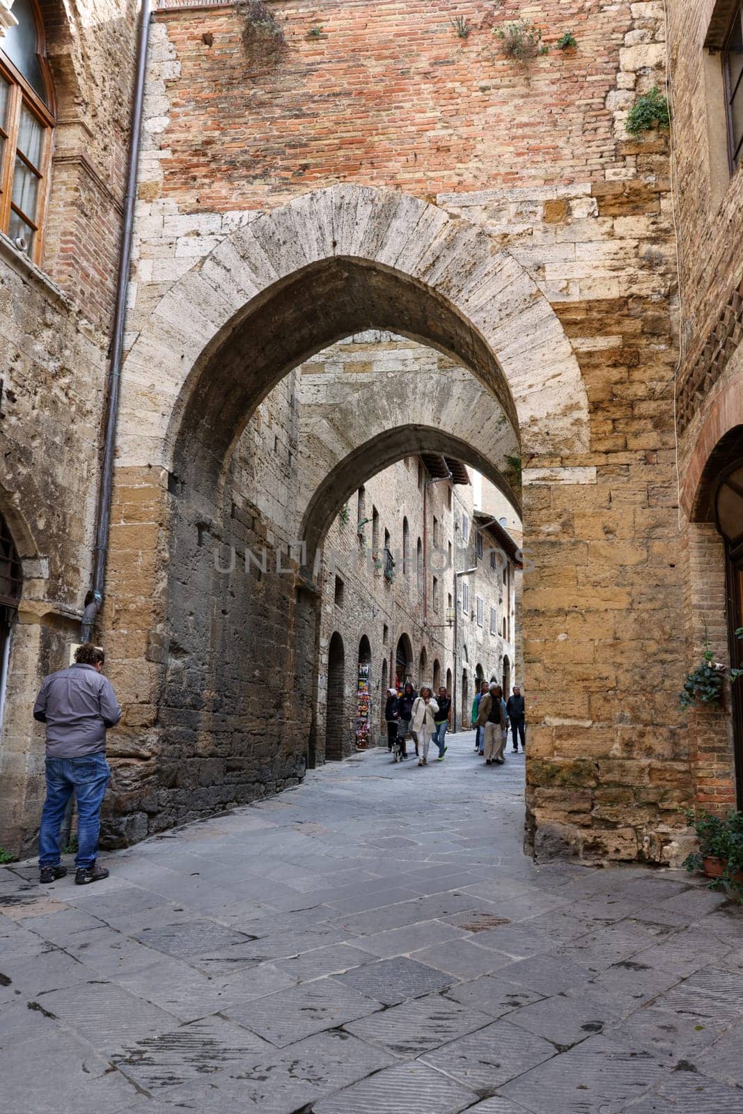 San Gimignano, Italy - Sept 17, 2022: Tourists on Via San Mateo in the medieval town of San Gimingnano. Tuscany, Italy