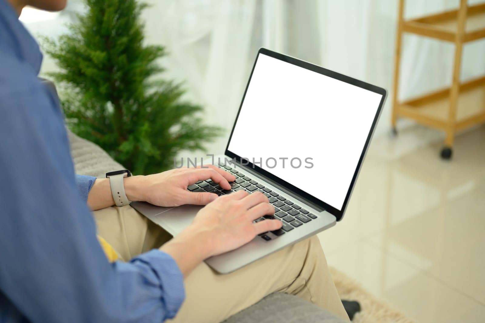Man hands using laptop with blank screen on sofa at his living room.