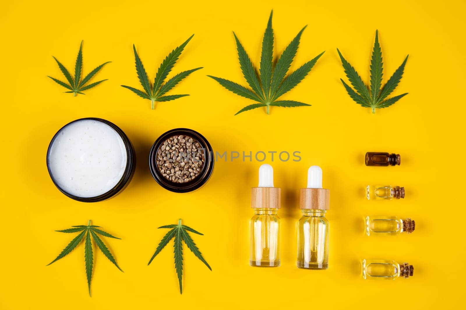 Set of essential oil in a glass bottle, with a pipette on a yellow background, top view