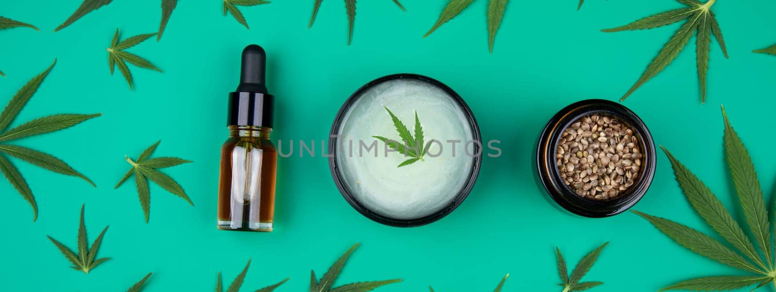 Flat lay composition with hemp oil and hemp leaves on green background