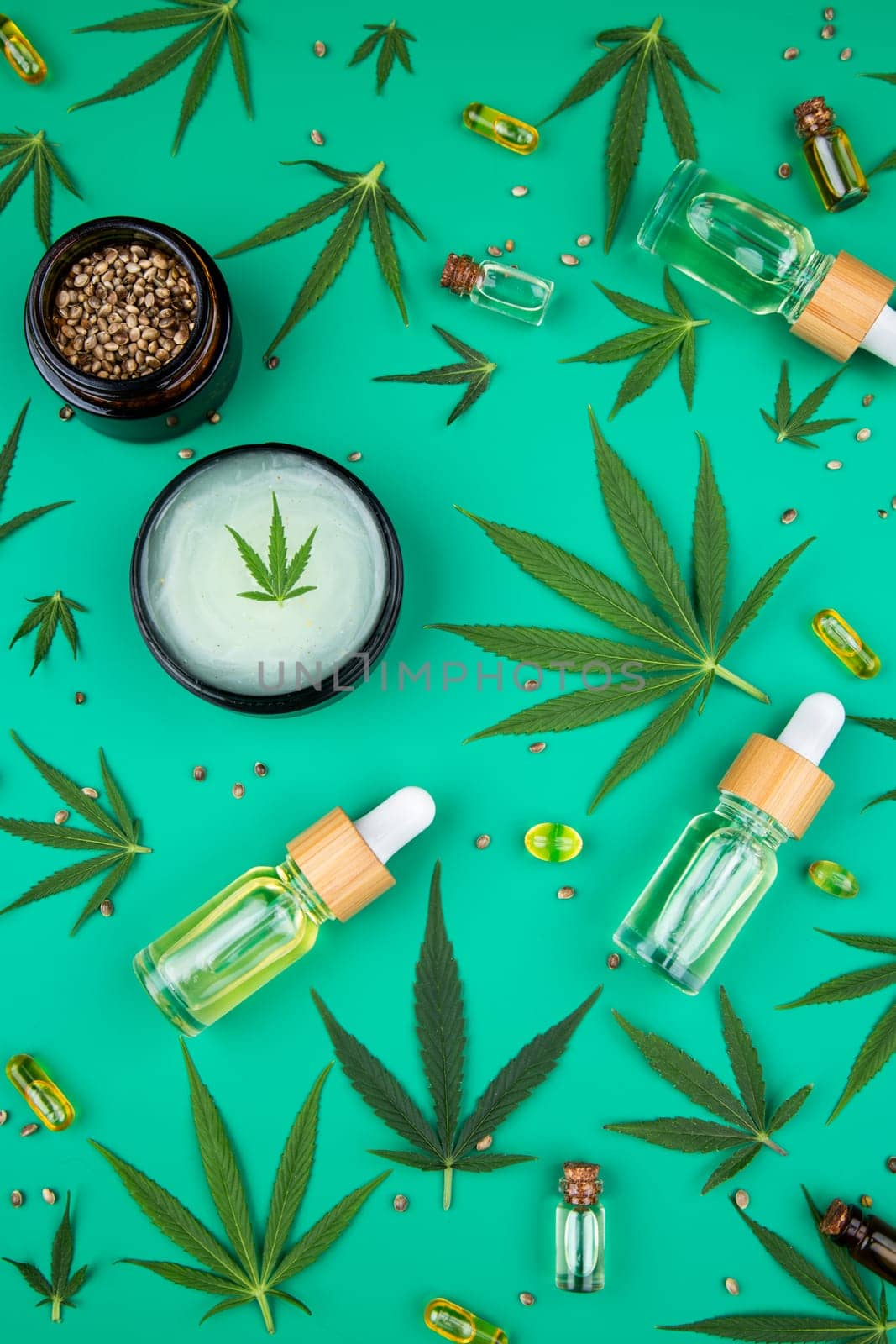 Flat lay composition with hemp oil and hemp leaves on green background