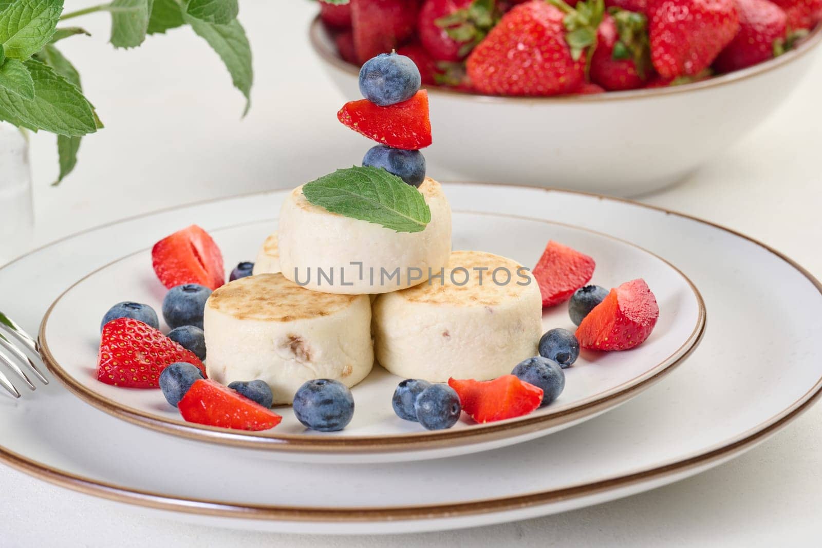 Stack of four cheesecakes on a plate with berries, blueberries, strawberries and cherries. Background white