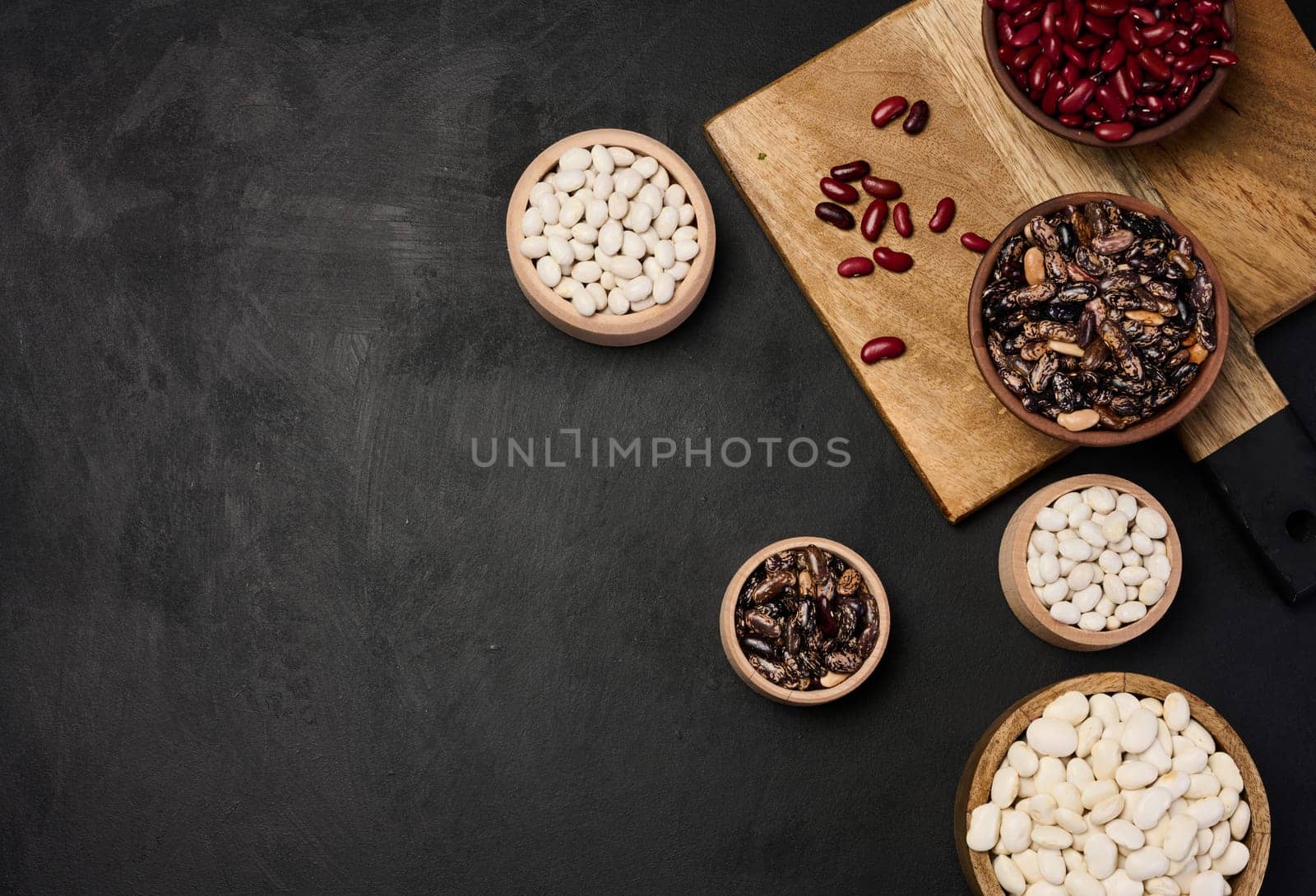 Raw white and red beans in a plate on a black table, top view. Assortment. Copy space