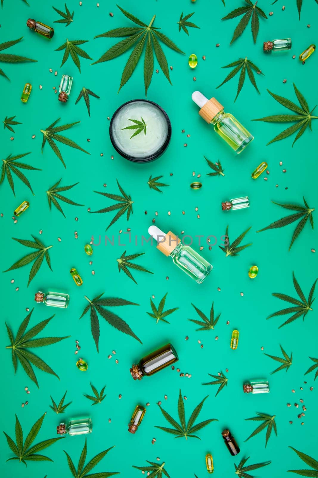 Flat lay composition with hemp oil and hemp leaves on green background